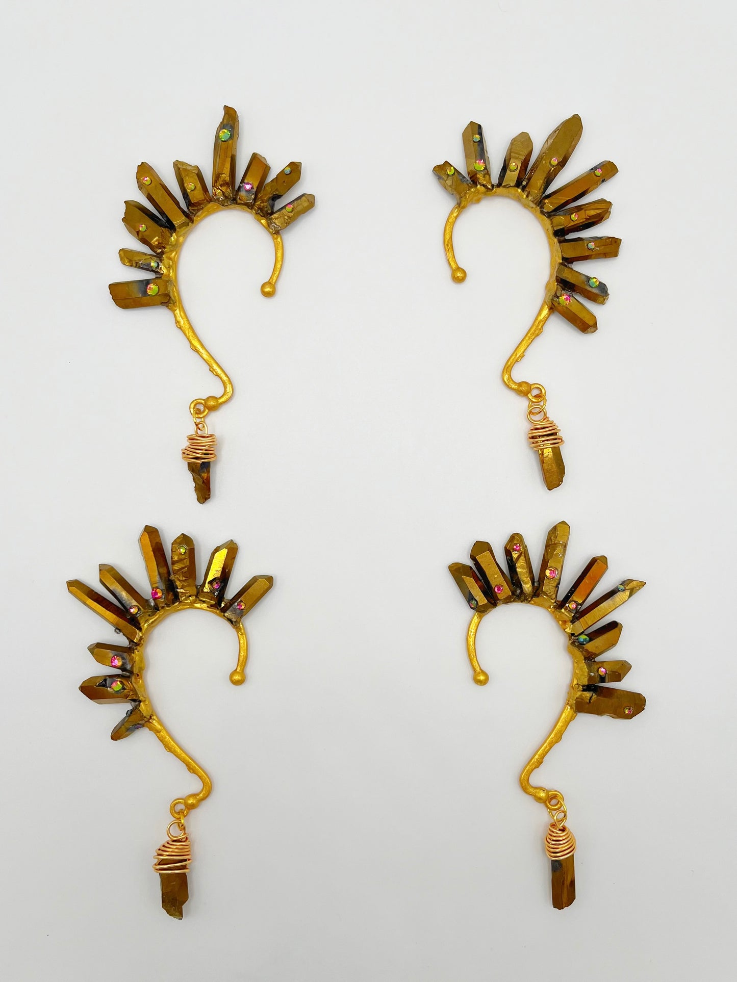 Four gold pyrite quartz crystal ear cuffs with rhinestones. A wire wrapped stone hangs from the bottom of each cuff.