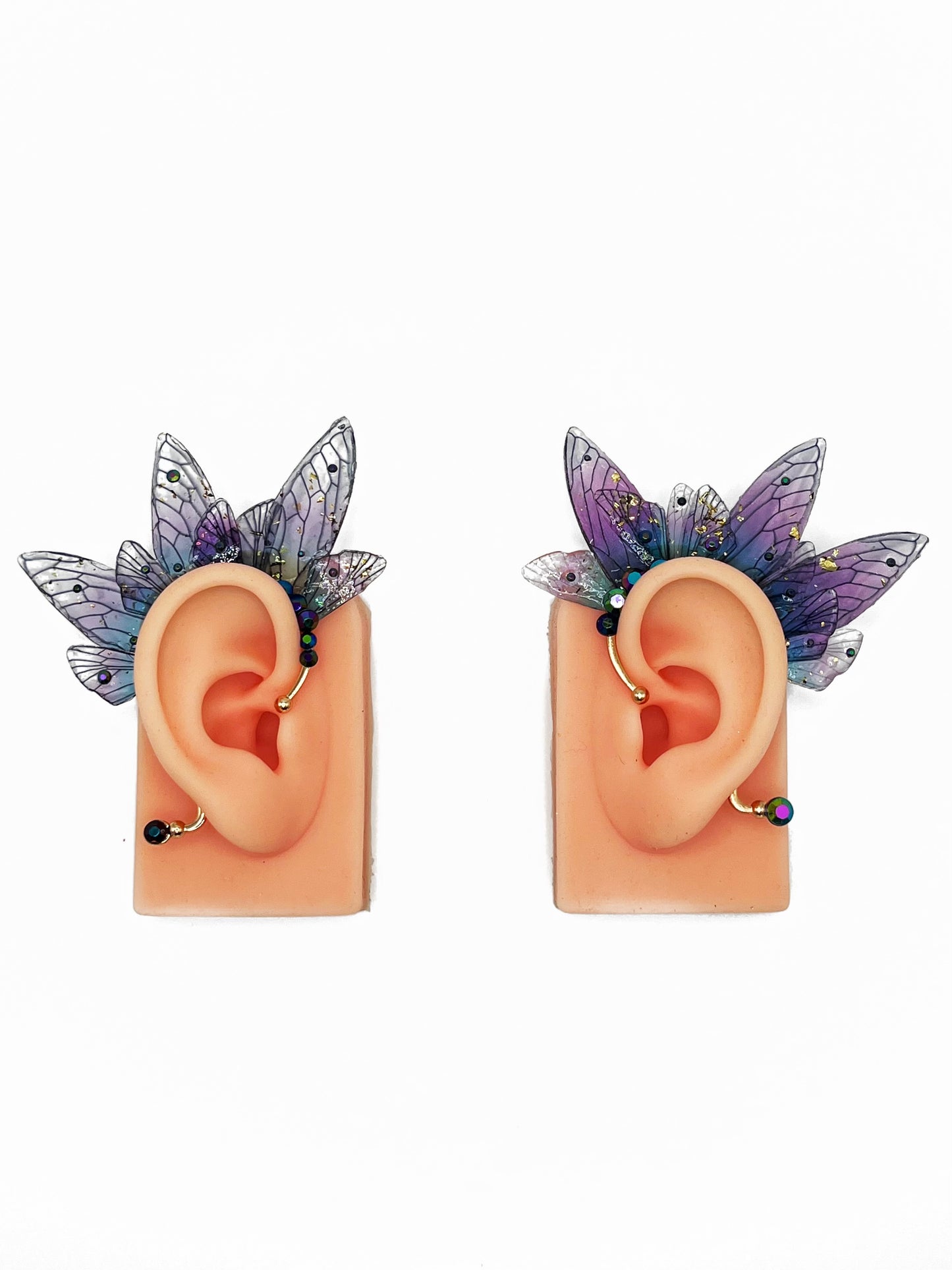 Purple fairy wing ear cuffs modeled on a pair of ears.
