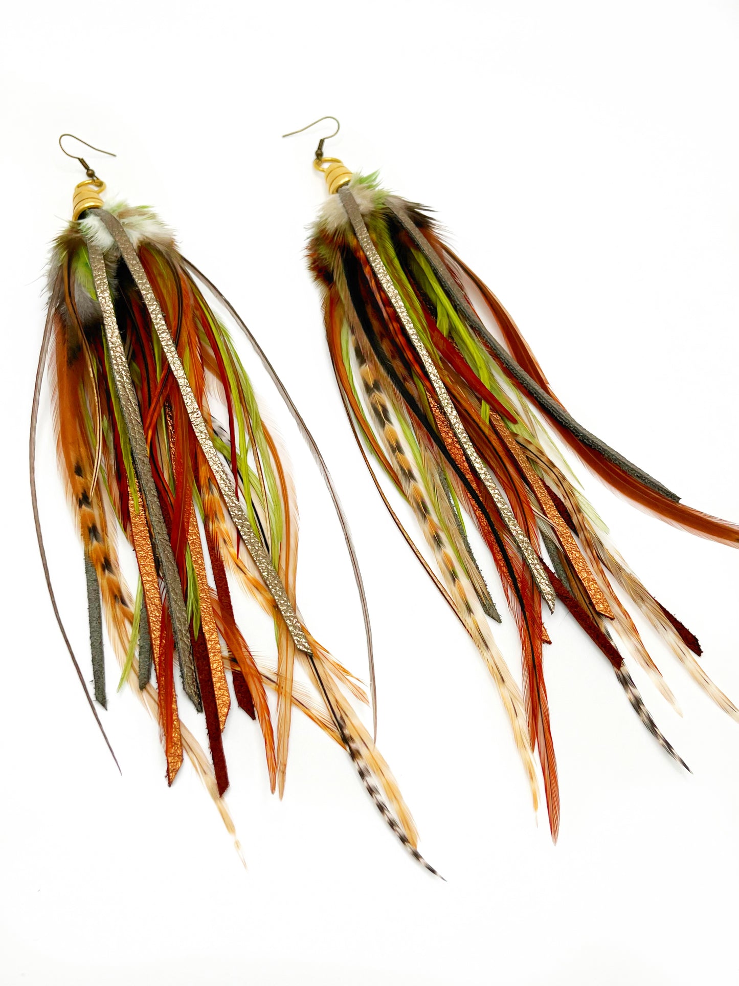 Long feather earrings in green and brown tones, with hand cut metallic leather. All feathers and leather hang from a gold colored bead cap.