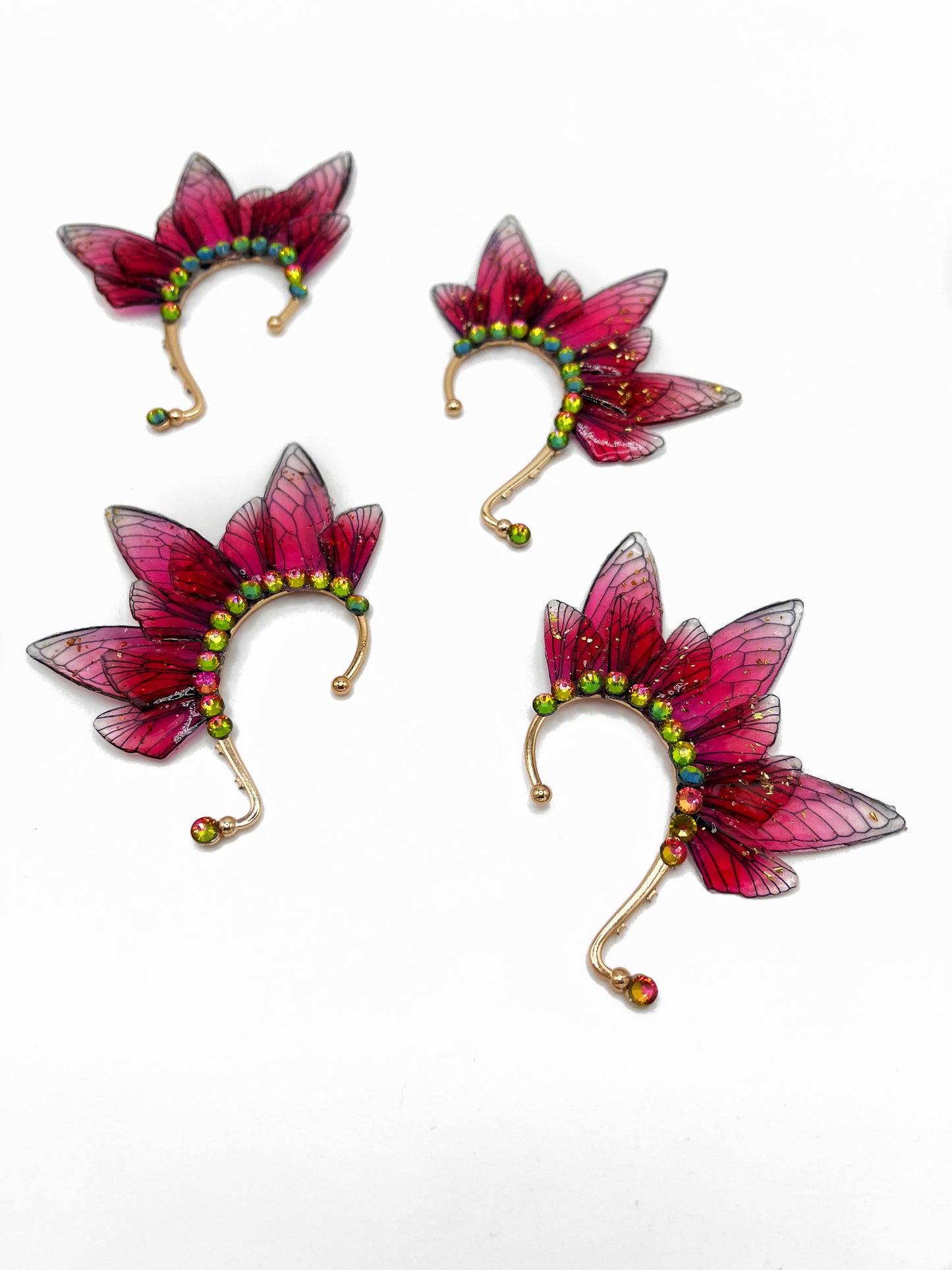 Four red fairy wing ear cuffs with green rhinestone accents.