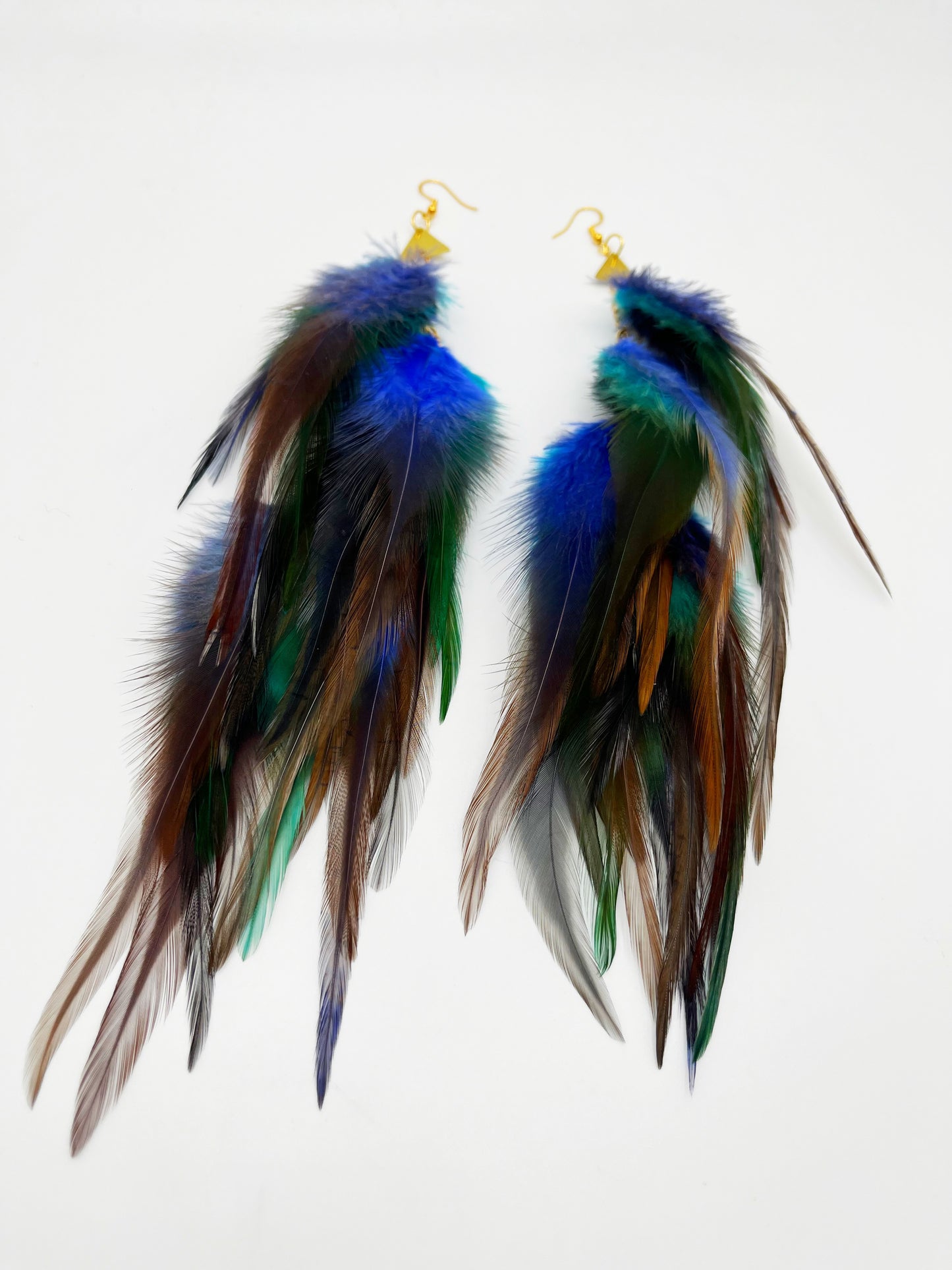 Long bohemian feather earrings in blue, gray and turquoise tones, with gold triangle pendants.