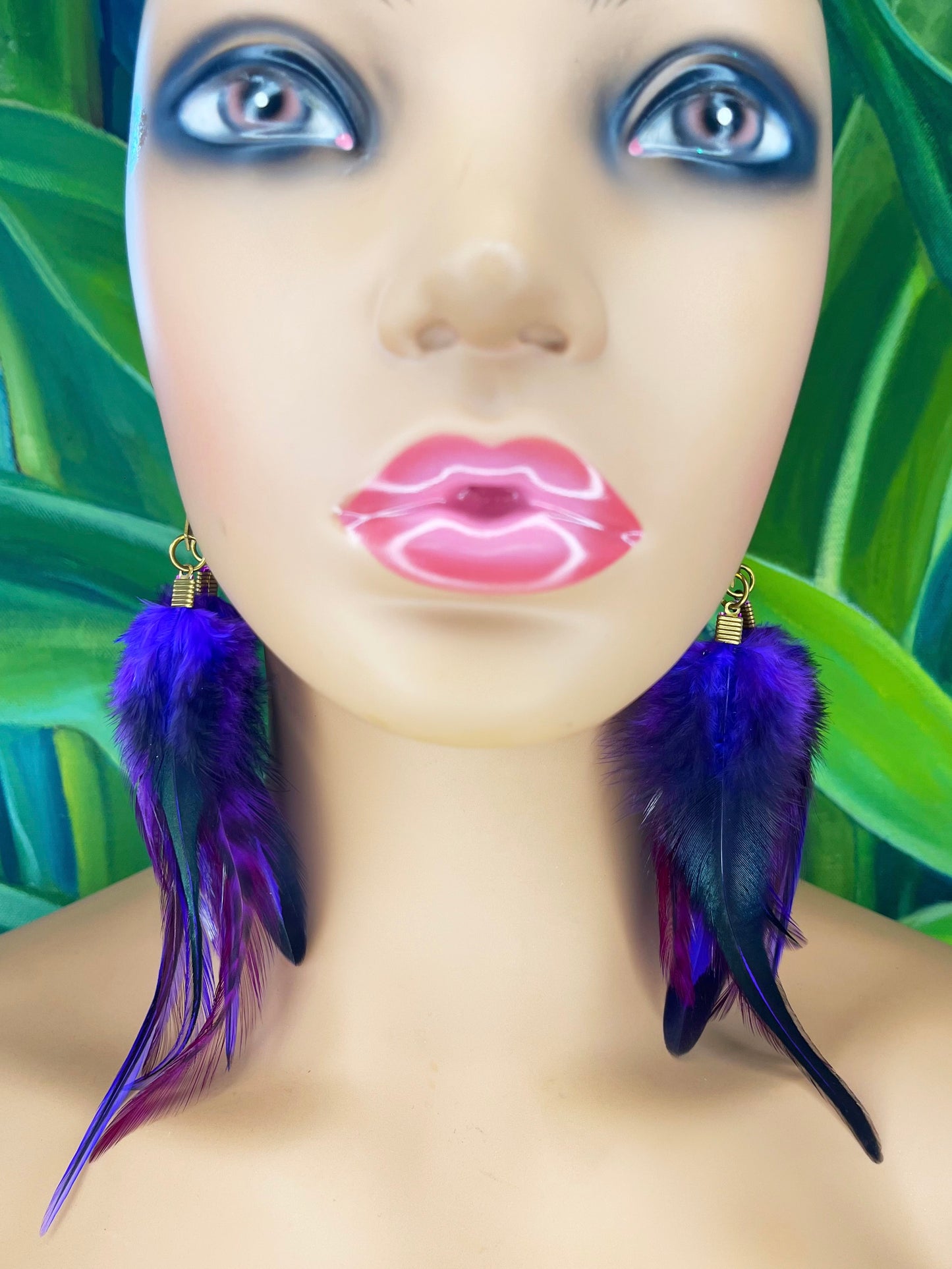 A mannequin is wearing long feather earrings, in shades of purple and black.