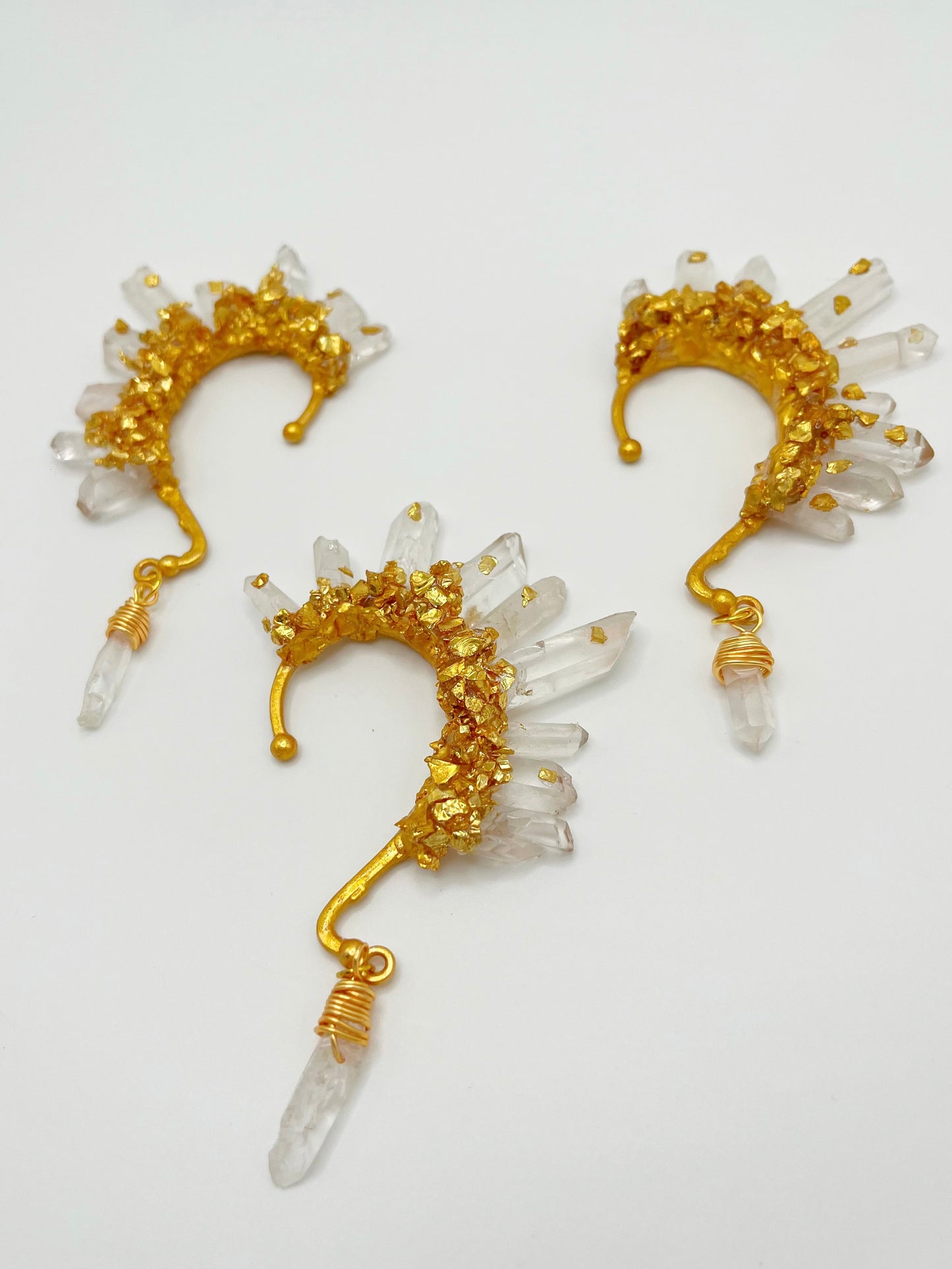 Clear quartz crystal ear cuffs with crushed gold accents. Wire wrapped quartz stones hang from the bottom of the cuffs.