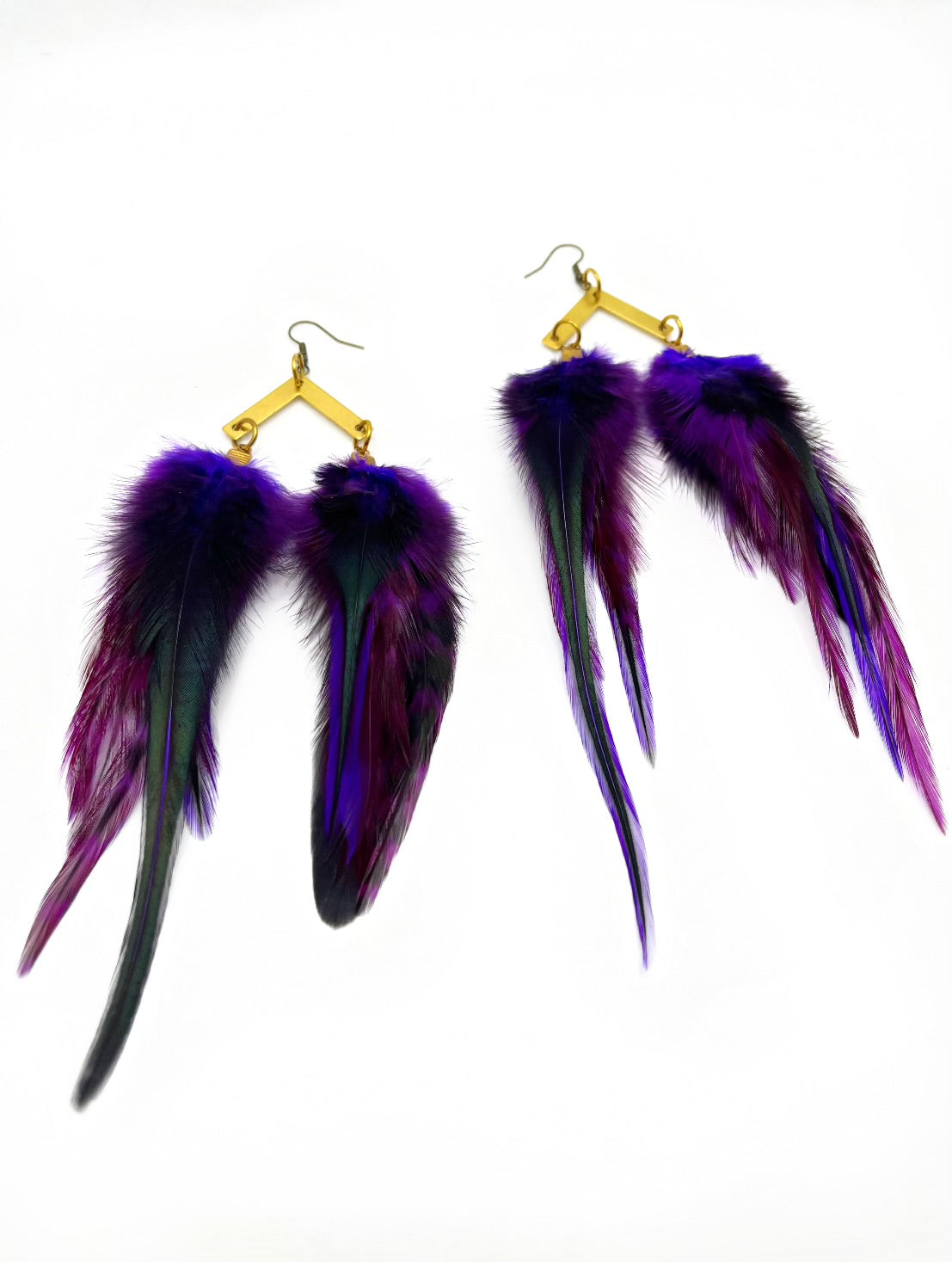 A pair of luxurious bohemian-style feather earrings, showcasing a rich gradient of purple to deep black. They are elegantly attached to gold geometric-shaped hardware, providing a sophisticated contrast against the white background. The feathers appear soft and fluffy, giving the earrings a dynamic and opulent look.