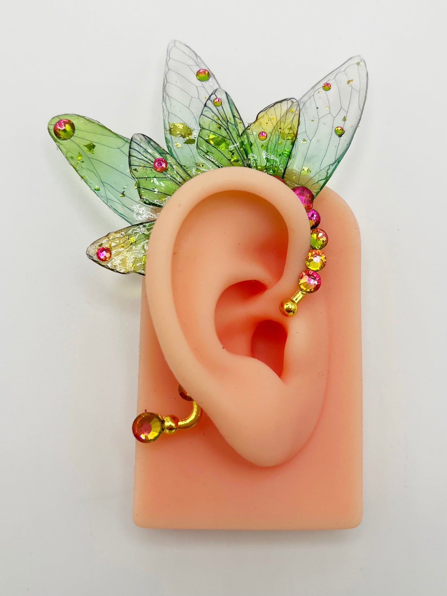Green fairy wing ear cuff with rhinestone accents, modeled on an ear.