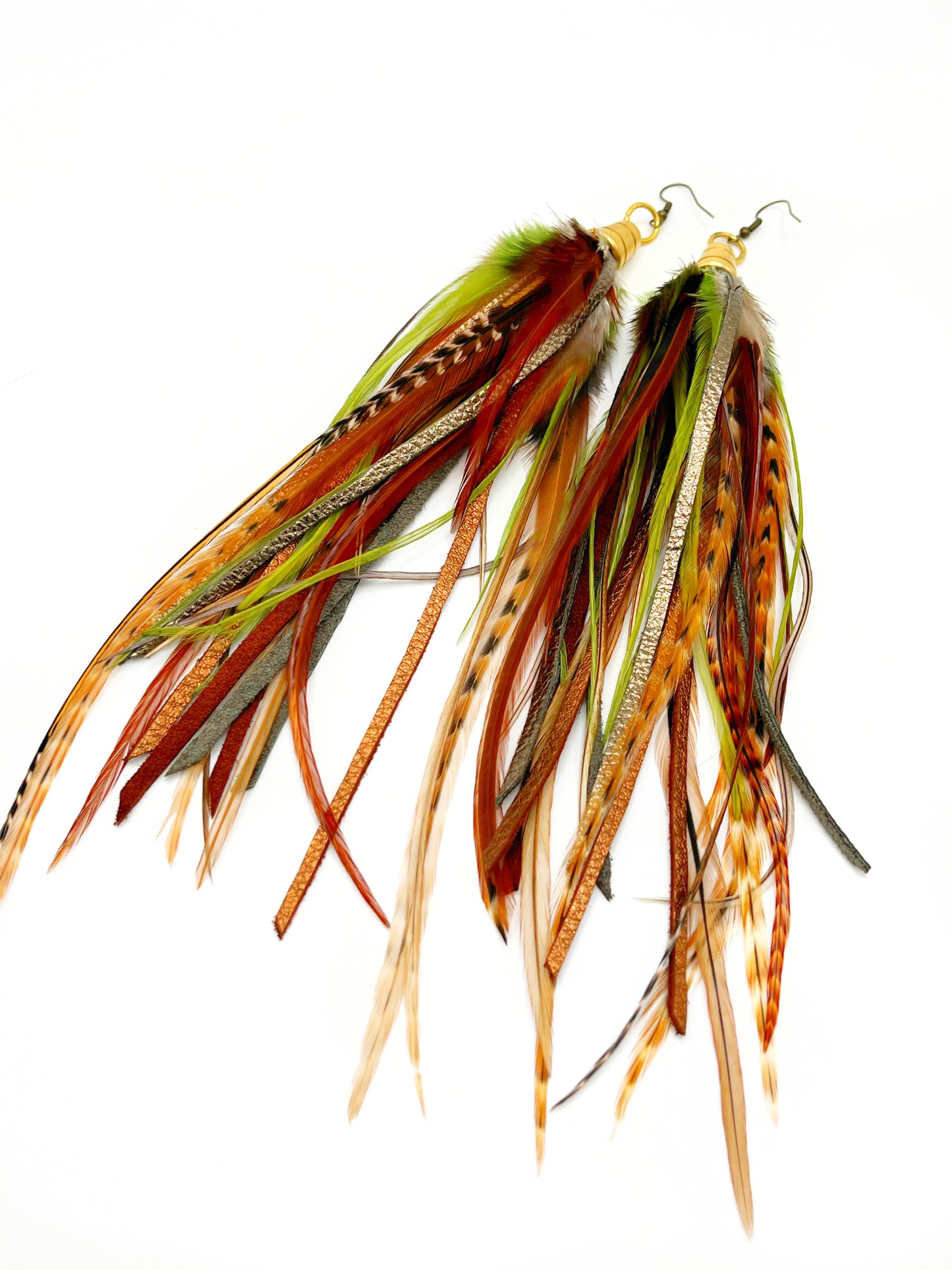 Long feather earrings in green and brown tones, with hand cut metallic leather. All feathers and leather hang from a gold colored bead cap.