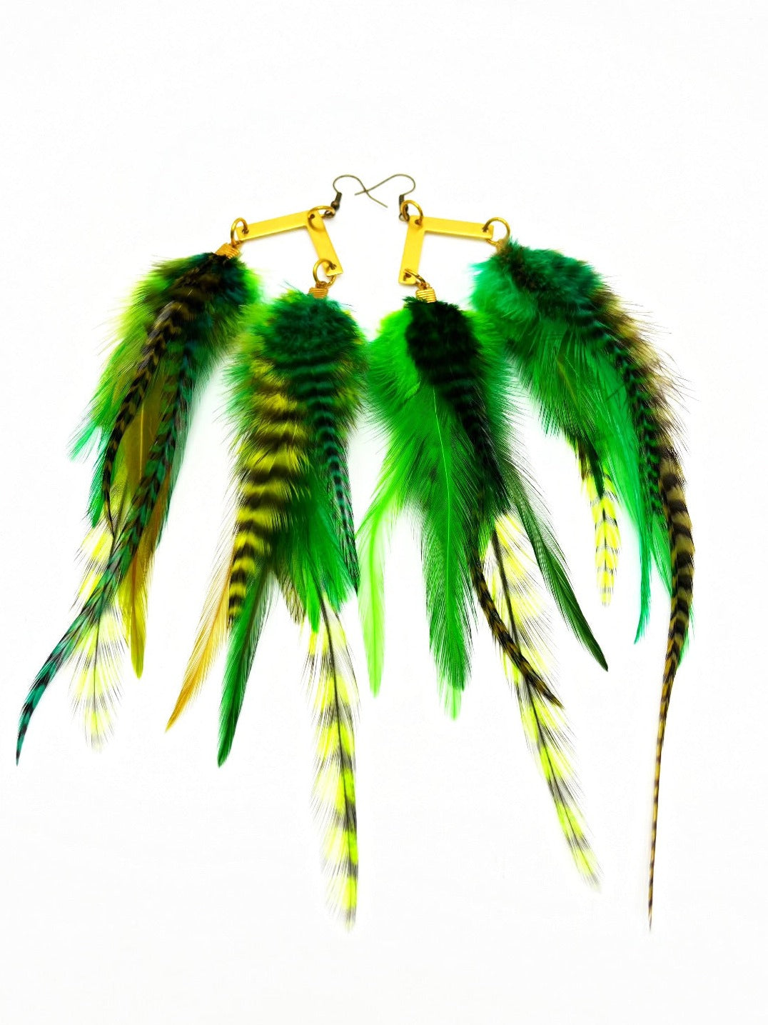 A pair of handmade earrings featuring an array of vibrant green and yellow grizzly feathers, attached to golden arrow pendants. The feathers vary in pattern and hue, some with striking black stripes, creating a lush, tropical aesthetic.