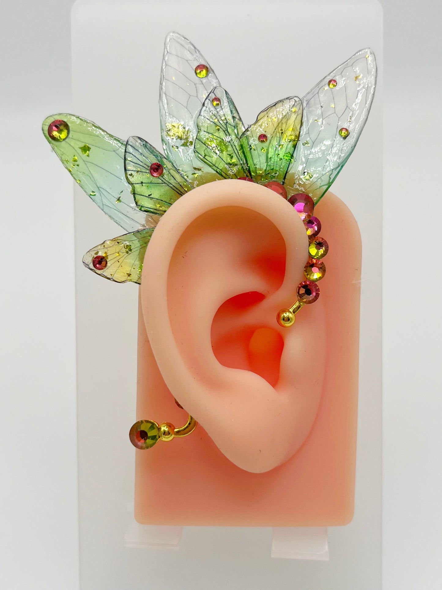 Green fairy wing ear cuff with rhinestone accents, modeled on an ear.