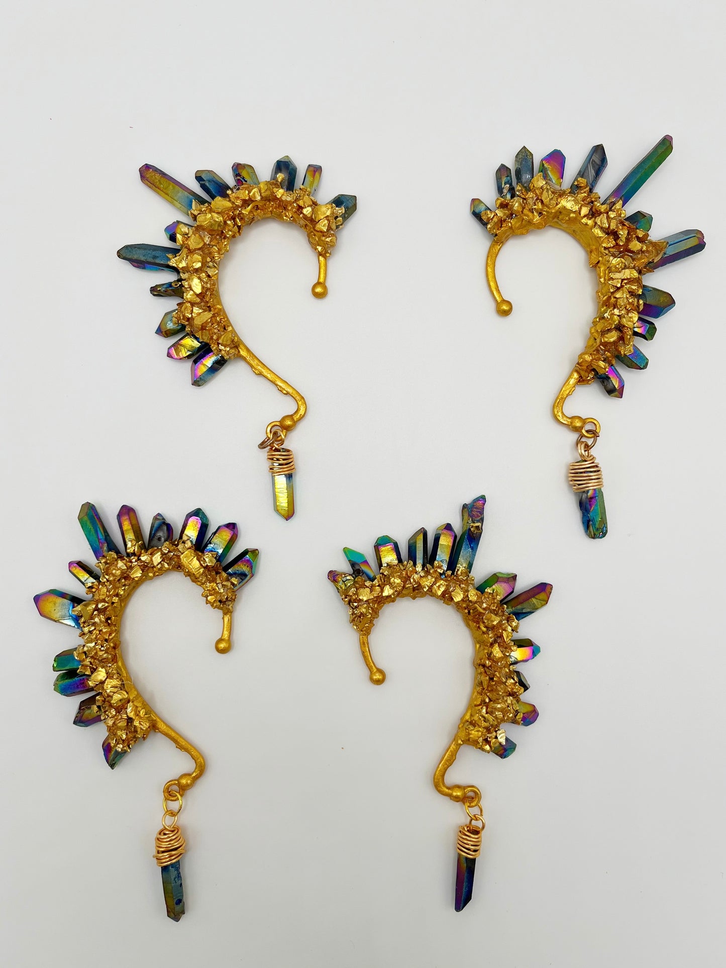 Four blue rainbow titanium coated quartz crystal ear cuffs with crushed gold accents. A wire wrapped stone hangs from the bottom of each cuff.