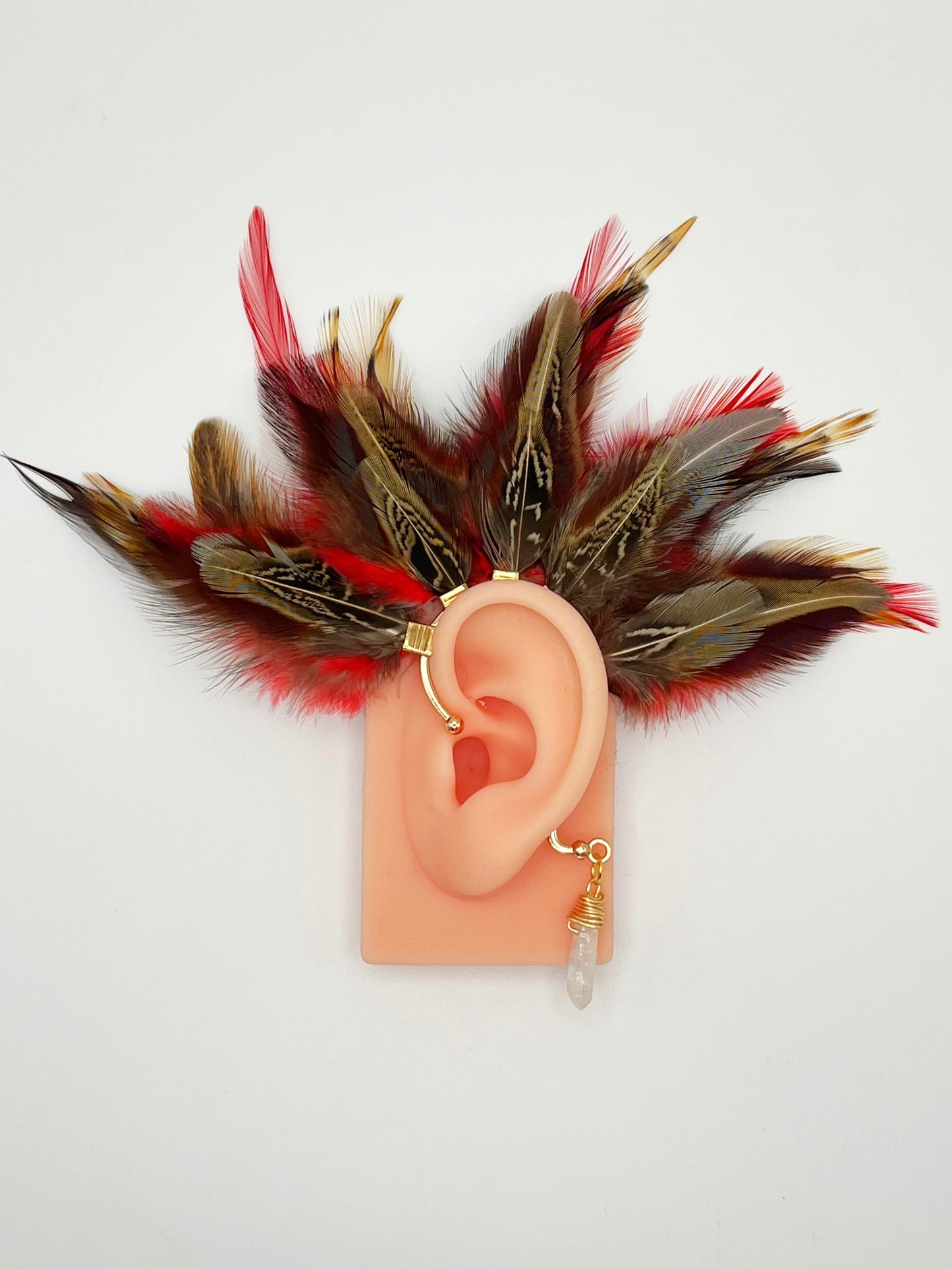Brown pheasant and vibrant red rooster feather ear cuff, modeled on an ear. A wire wrapped quartz stone hangs from the cuff behind the ear.