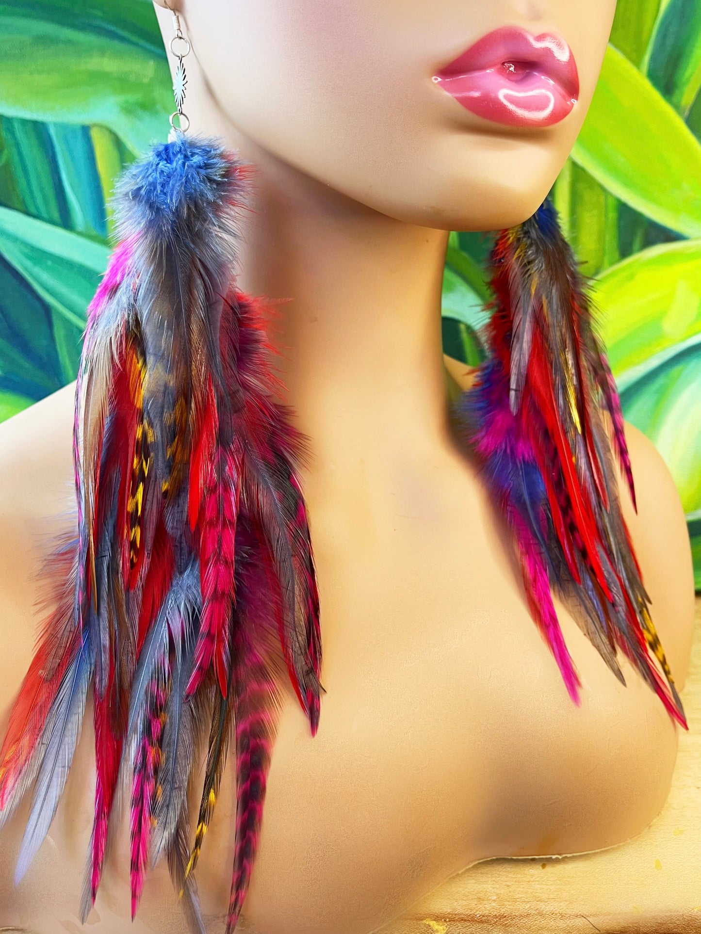 A mannequin head wearing long bohemian feather earrings, in cascading shades of gray, yellow, red, pink and blue.