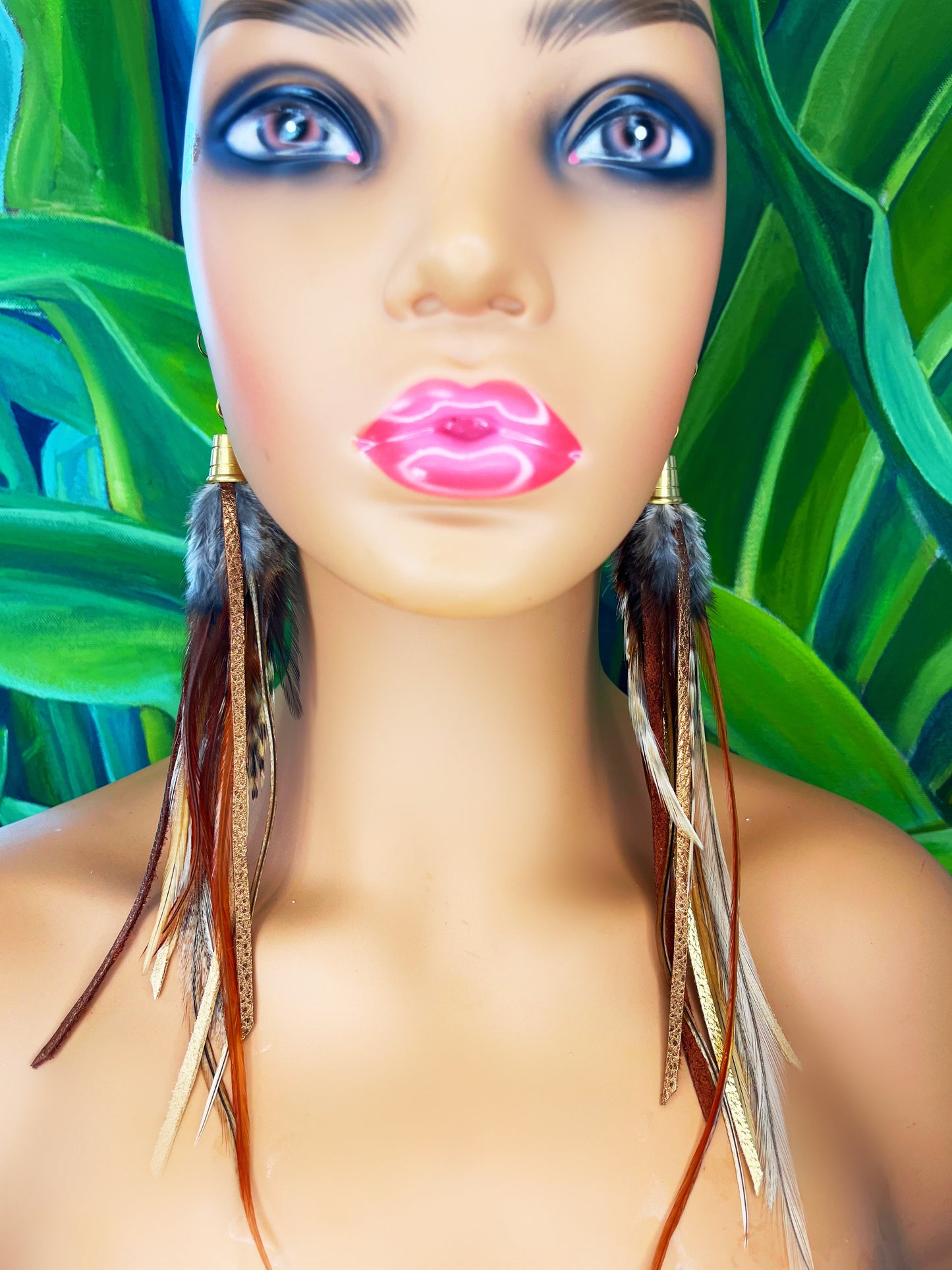 A model wearing dark brown feather earrings with metallic gold and bronze leather strips, hanging from a gold colored cap pendant.