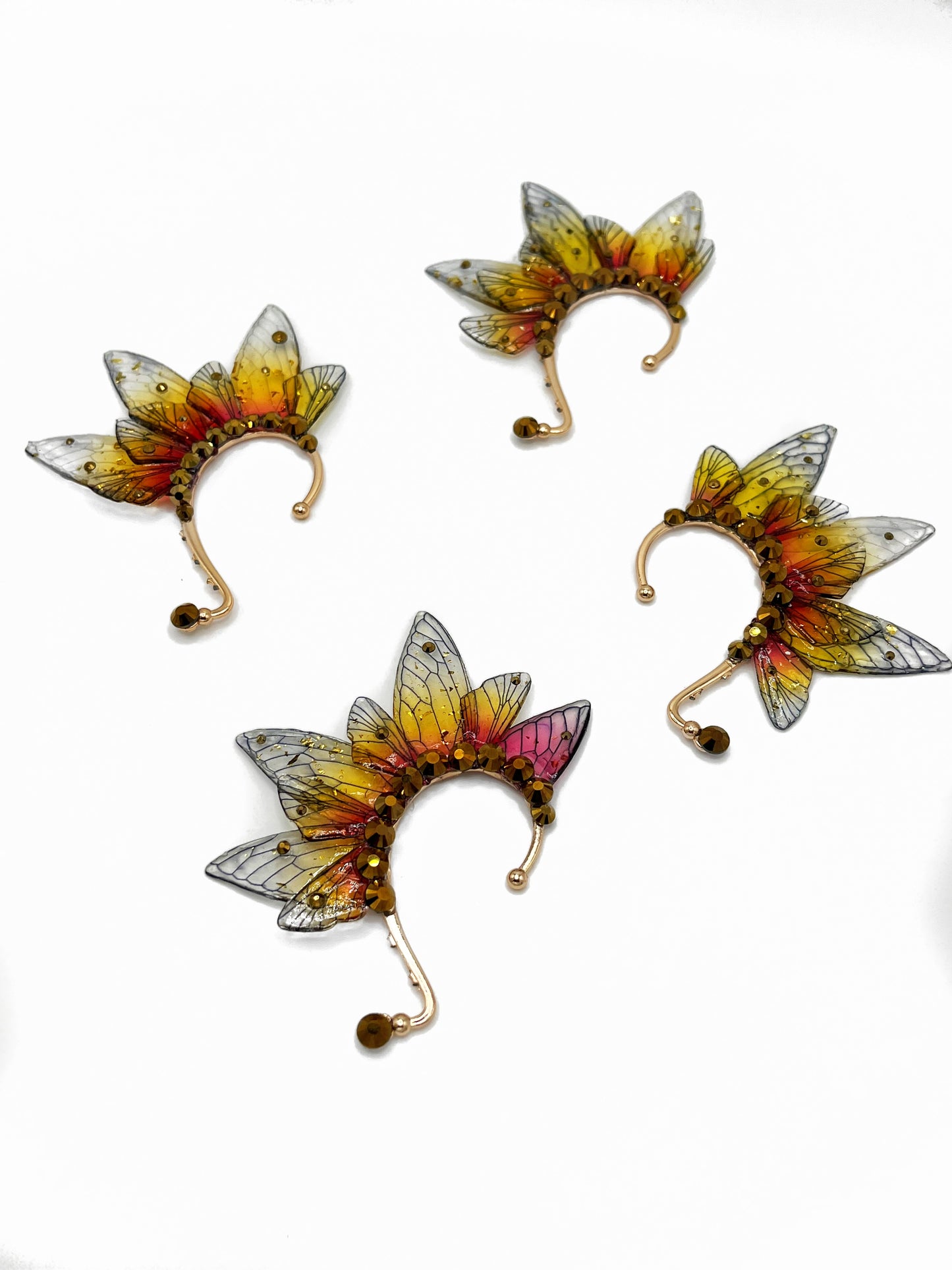 Four yellow and red fairy wing ear cuffs with gold rhinestones.