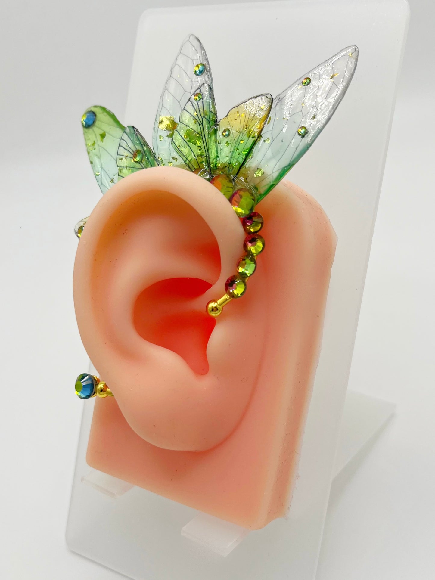 Green fairy wing ear cuff with rhinestone accents, modeled on an ear.