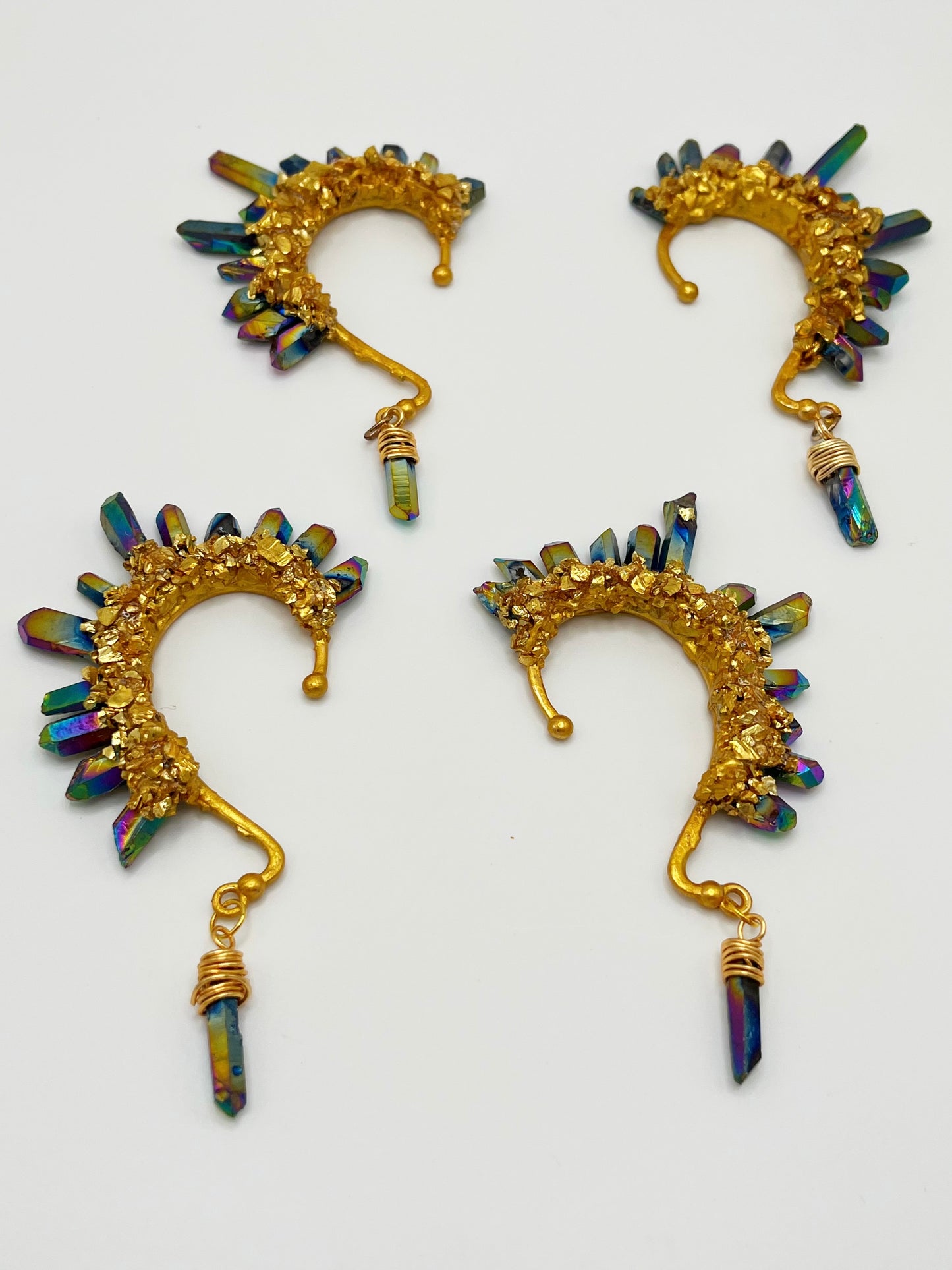 Four blue rainbow titanium coated quartz crystal ear cuffs with crushed gold accents. A wire wrapped stone hangs from the bottom of each cuff.