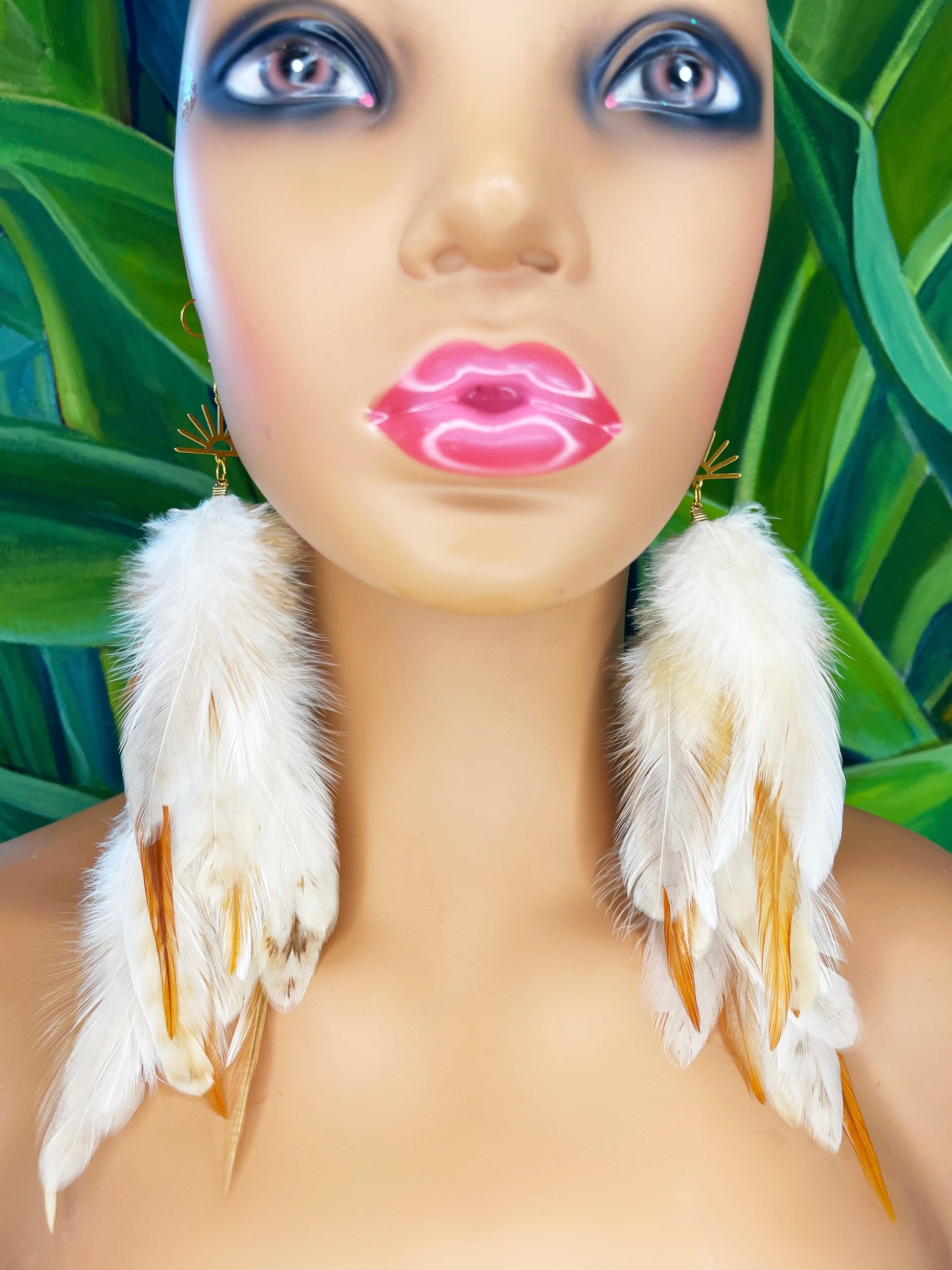 Long bohemian feather earrings in cream and beige tones, modeled on a mannequin. 