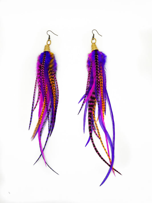 Long feather earrings in vibrant pink, purple and orange tones, with gold colored pendants. 