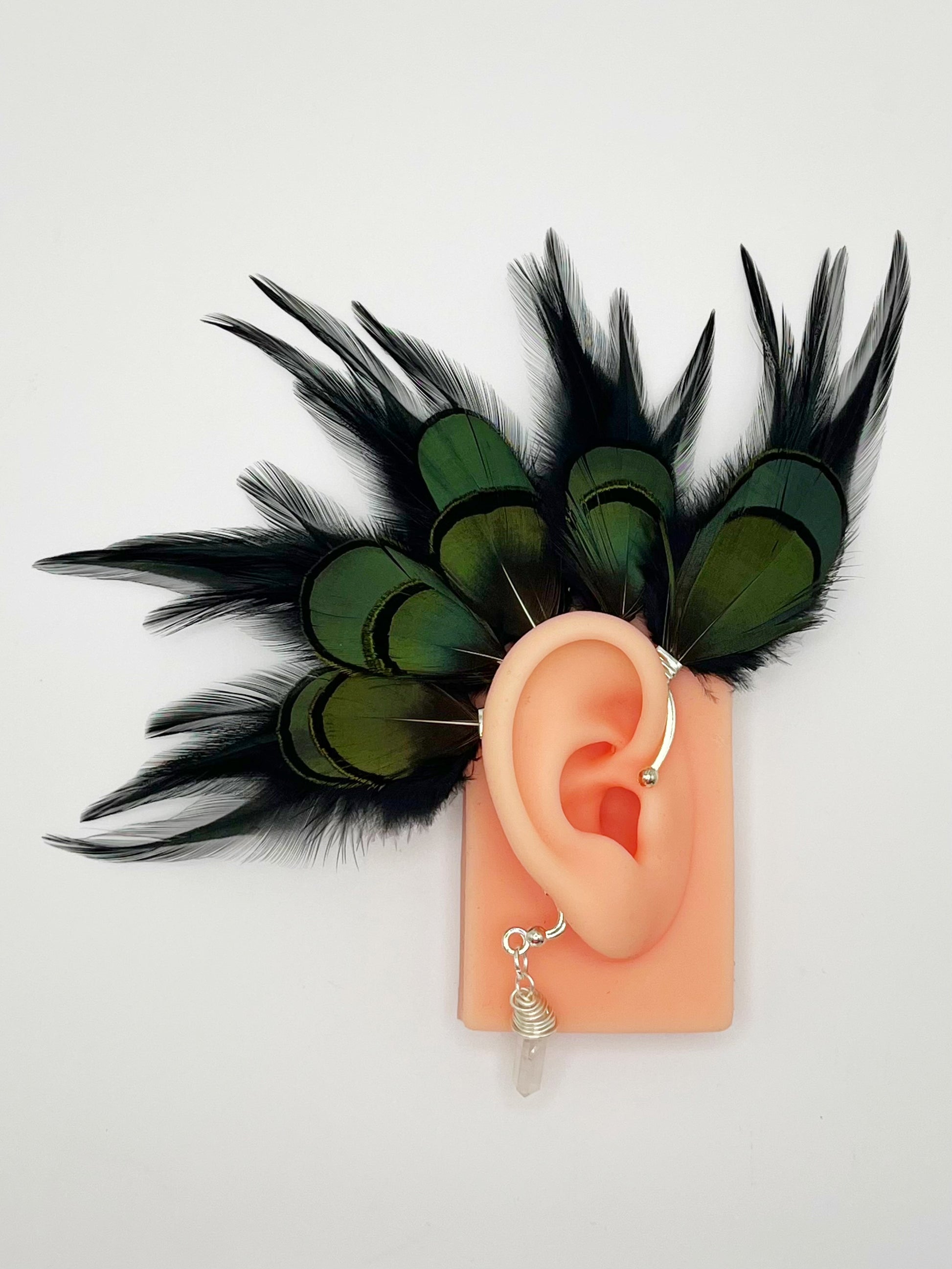 Black rooster and emerald green lady Amherst feather ear cuff, modeled on an ear. A wire wrapped quartz stone dangles from the bottom of the cuff behind the ear.