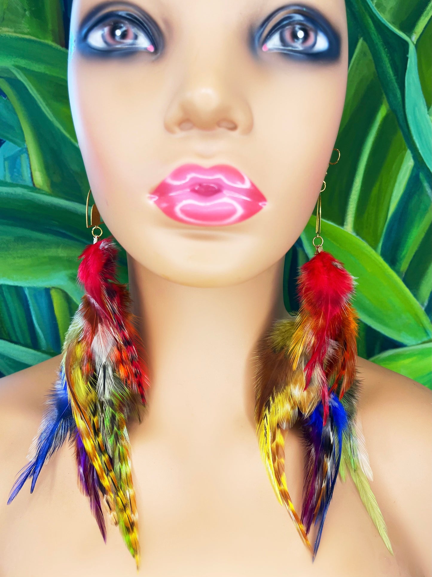 Long bohemian feather earrings in rainbow colors worn on a mannequin. 