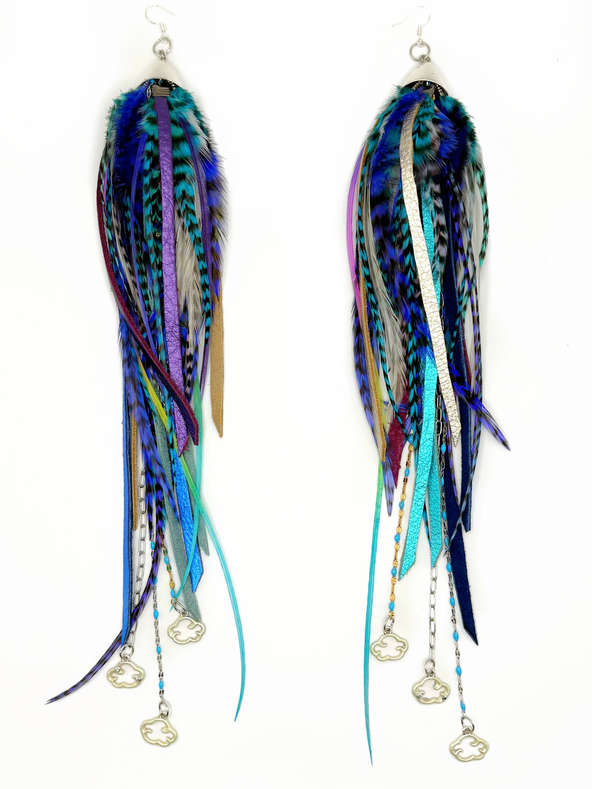 A pair of long, dangling feather and ribbon earrings with silver fish-shaped charms, featuring a mix of blue, teal, purple, and black feathers on a white background.