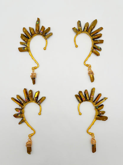Four gold pyrite quartz crystal ear cuffs with rhinestones. A wire wrapped stone hangs from the bottom of each cuff. 