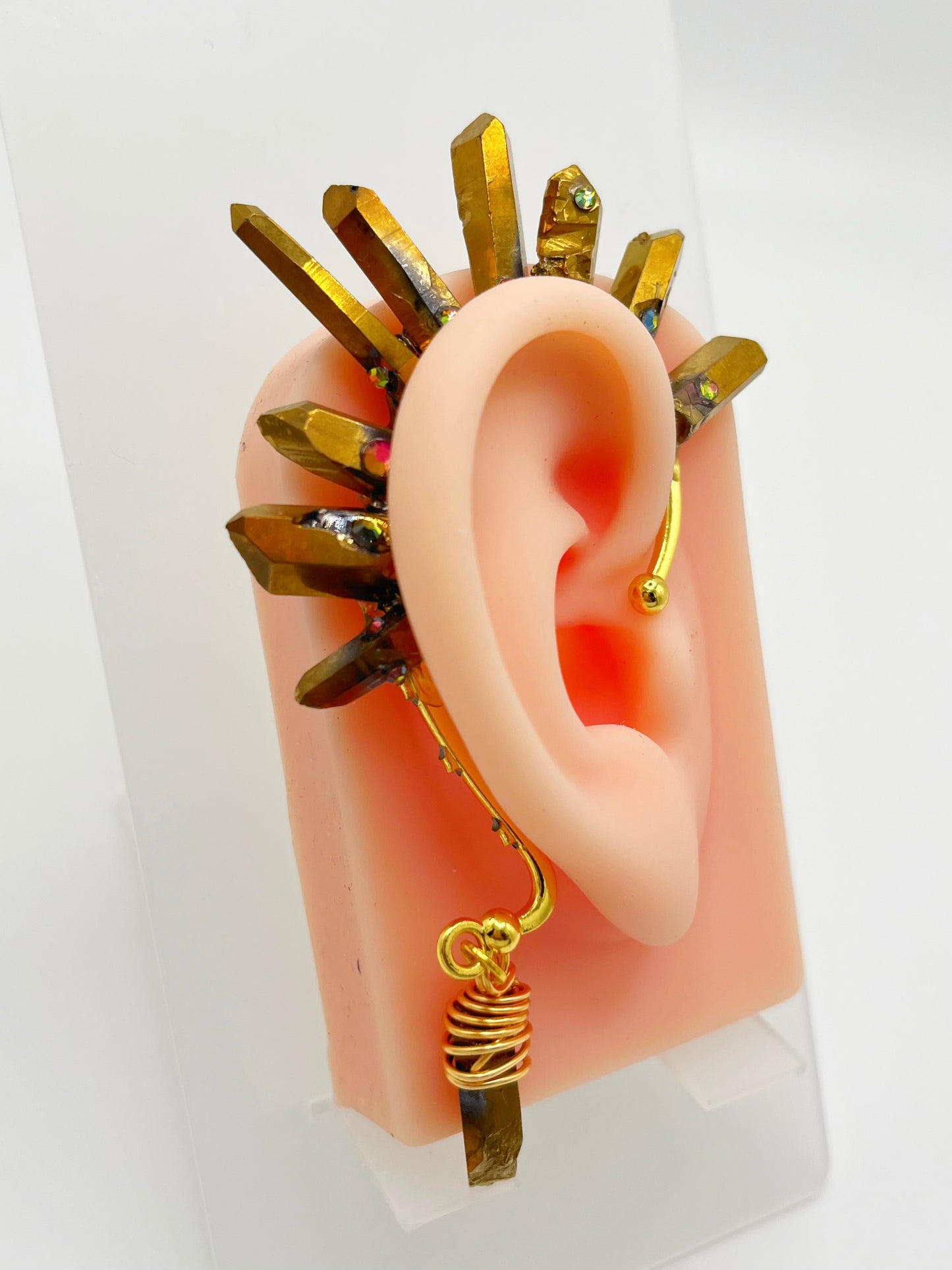 Gold pyrite quartz crystal ear cuff with rhinestones, modeled on an ear. A wire wrapped stone hangs from the bottom of the cuff behind the ear. 