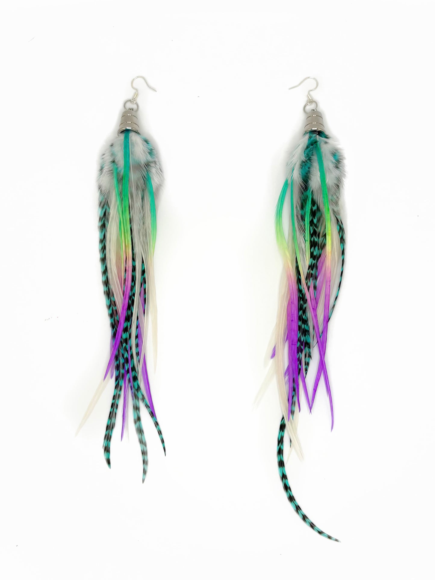 A pair of long dangling feather earrings on a plain white background. Each earring has silver fishhook ear wires, a small silver cap, and a cluster of feathers in white, green, purple, and black with turquoise striping.