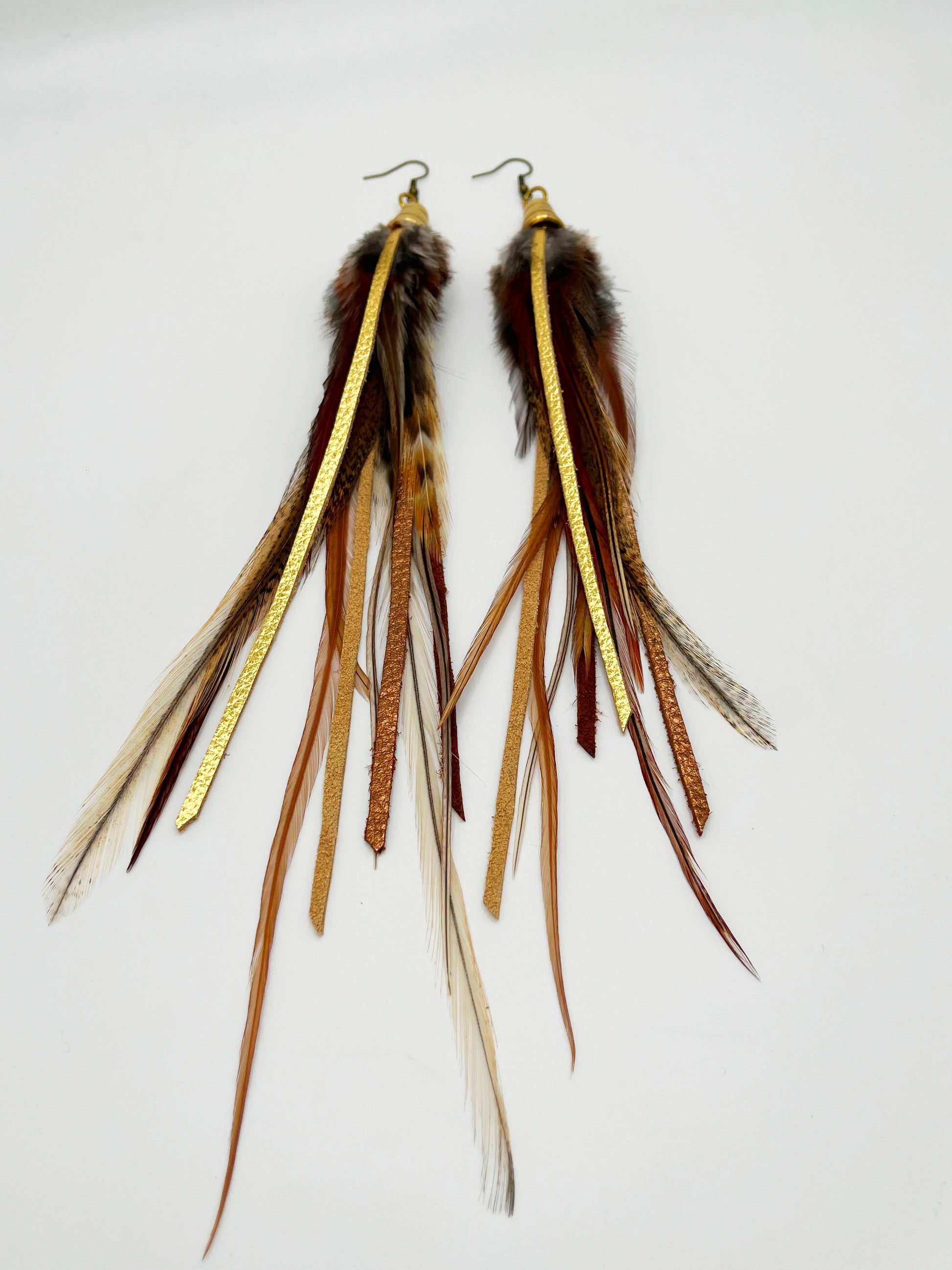 Dark brown feather earrings with metallic gold and bronze leather strips, hanging from a gold colored cap pendant.