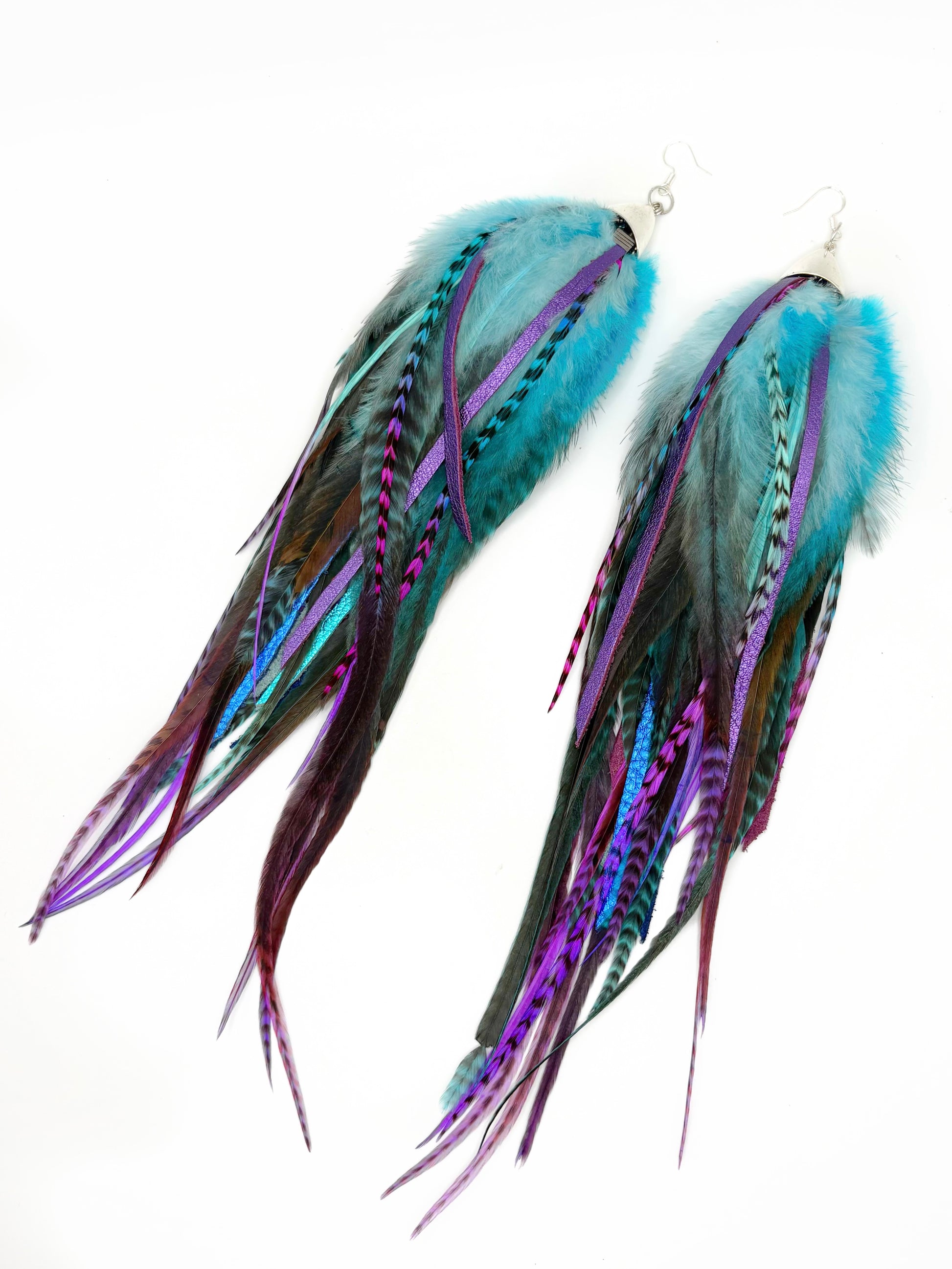 Pair of feather earrings with blue and purple hues on a white background