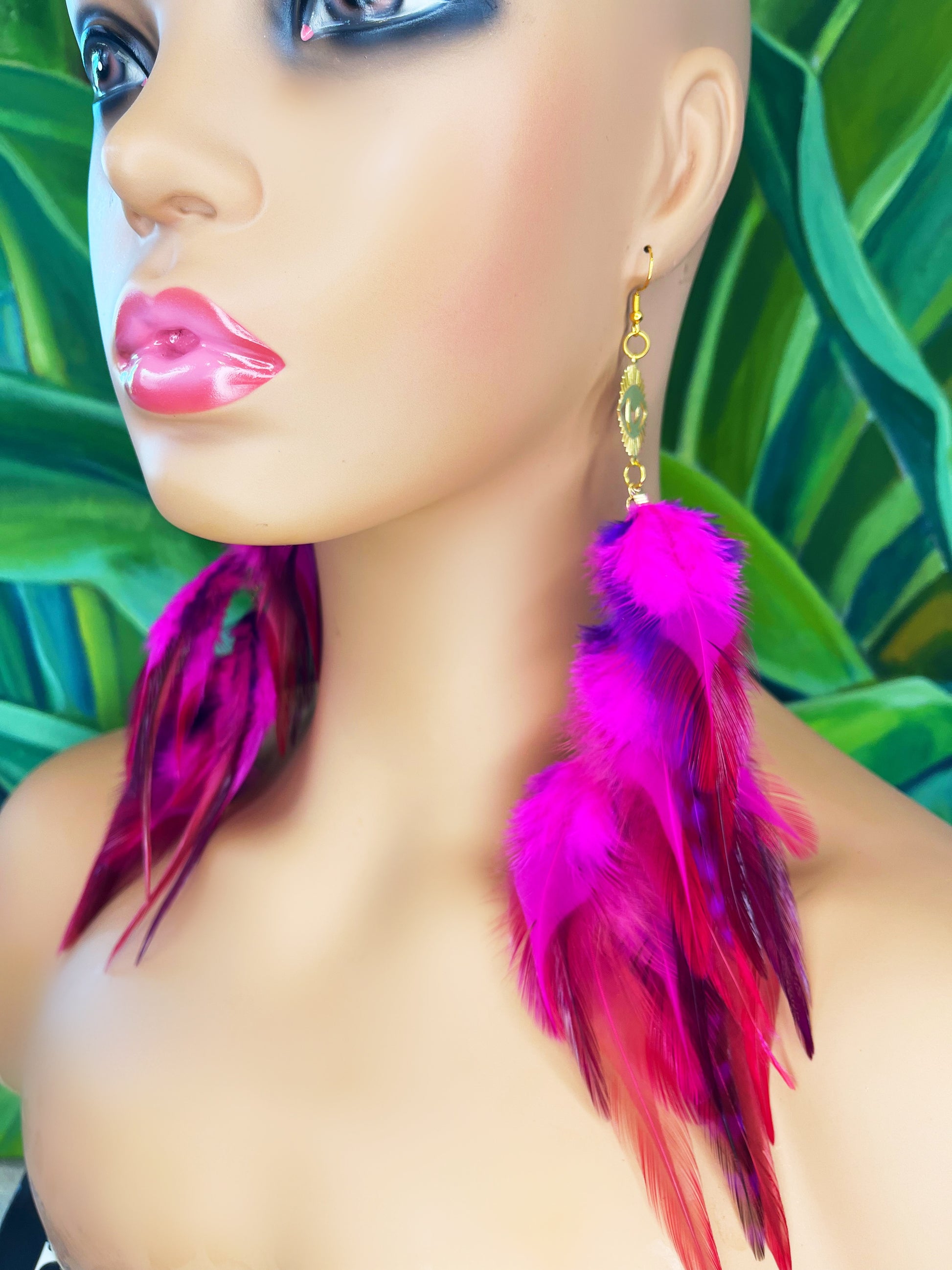 Long bohemian feather earrings in bright pink colors, modeled on a mannequin. 