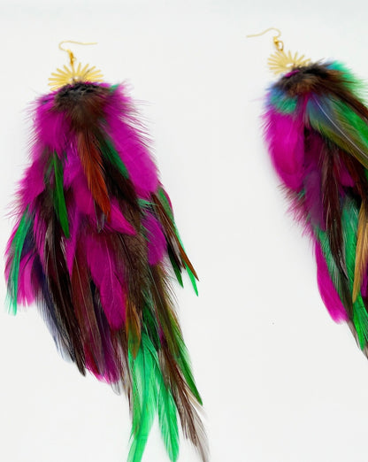 Colorful long feather earrings with gold sunburst pendants, featuring hues of purple, green, and pink against a white background, ideal for boho chic fashion.