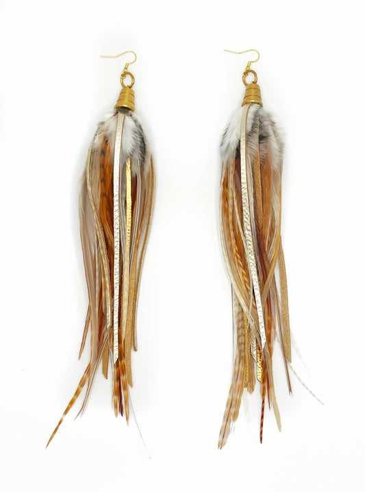 Long voluminous feather and leather earrings in beige, gold and white tones. 