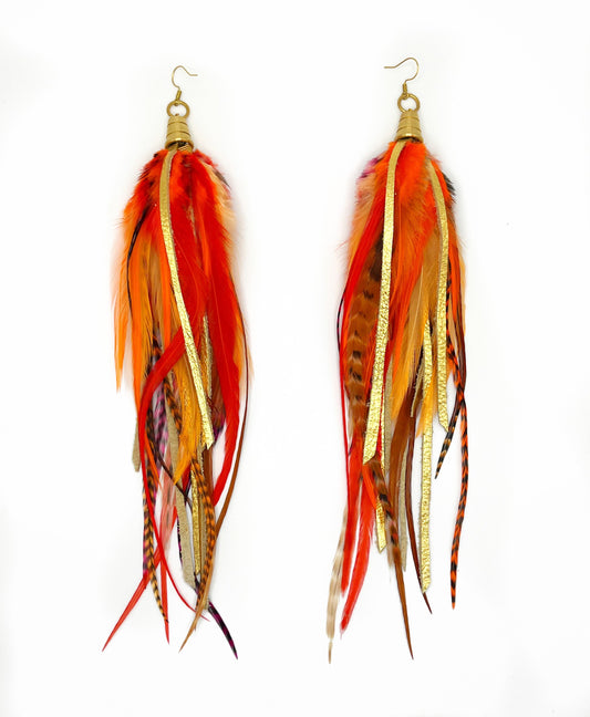 Long bohemian feather earrings with bright orange feathers, metallic gold leather and gold colored pendants. 