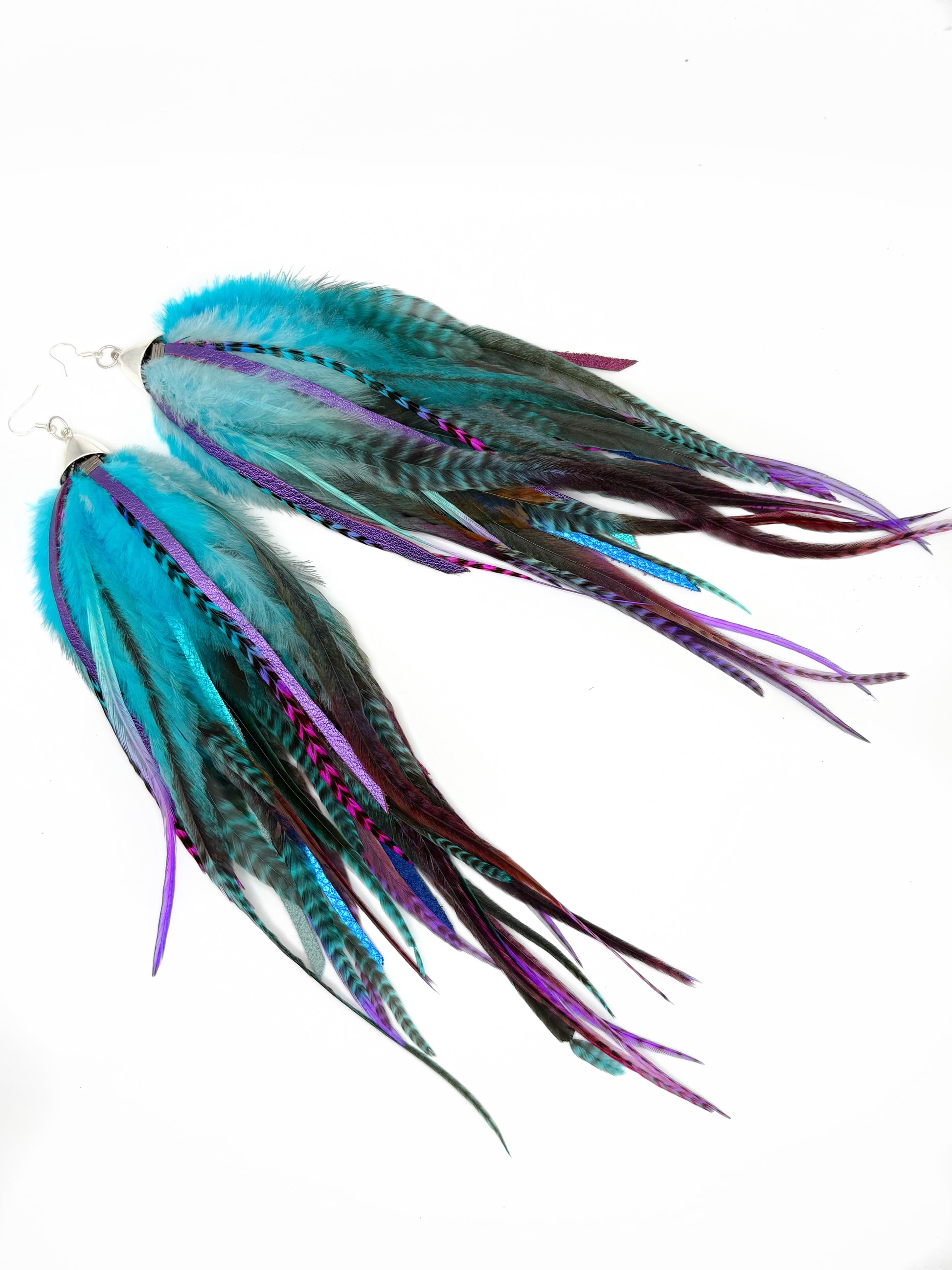 Two colorful fishing lures with blue, purple, and green feathers on a white background