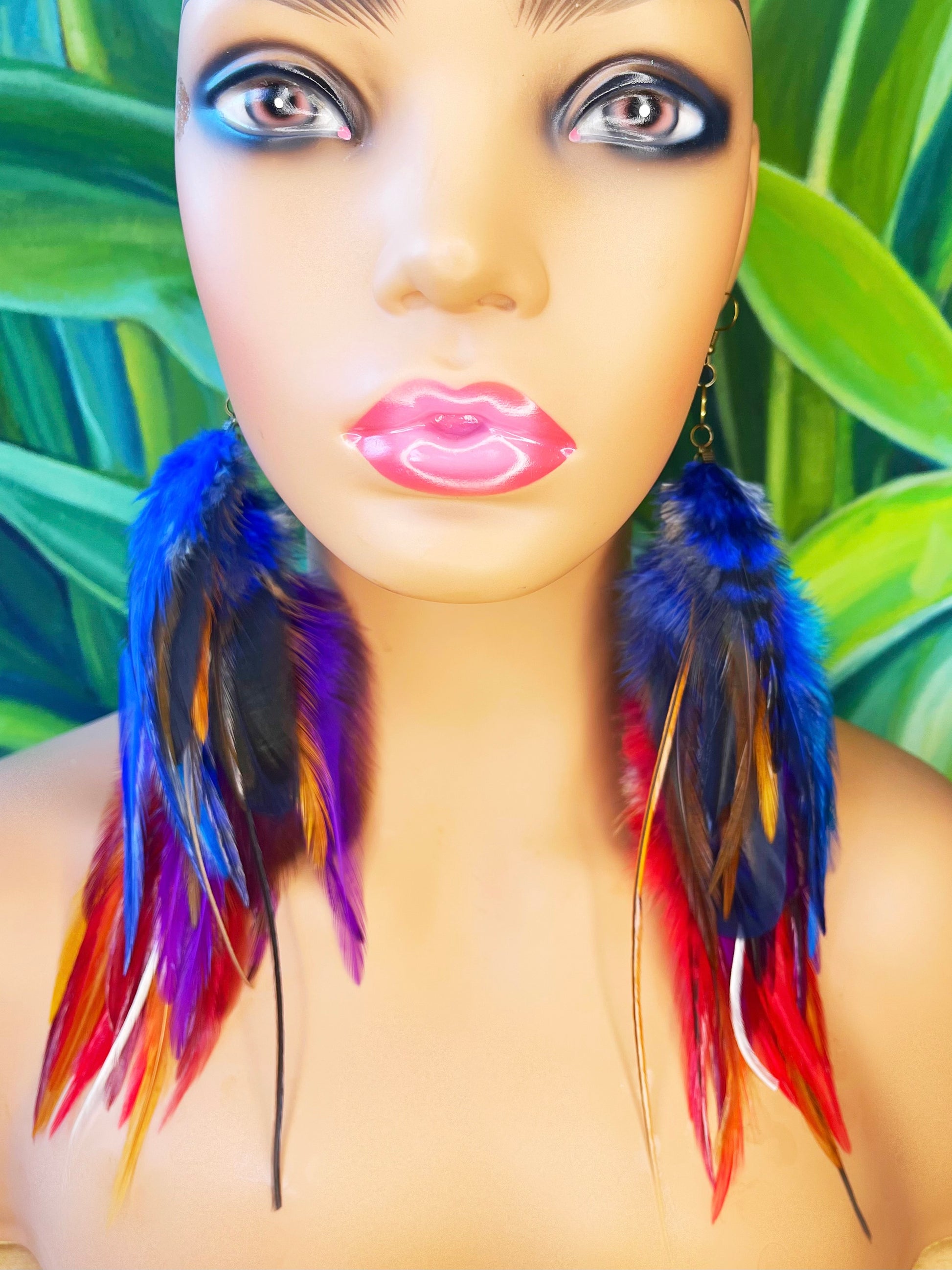 Vibrant long feather earrings displayed on a mannequin, showcasing bold colors of blue, purple, and red against a tropical background, ideal for statement-making bohemian style.