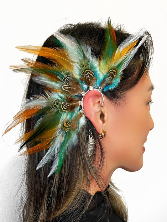 Rooster and pheasant feather ear cuff in green, turquoise and beige tones, modeled on a woman. 