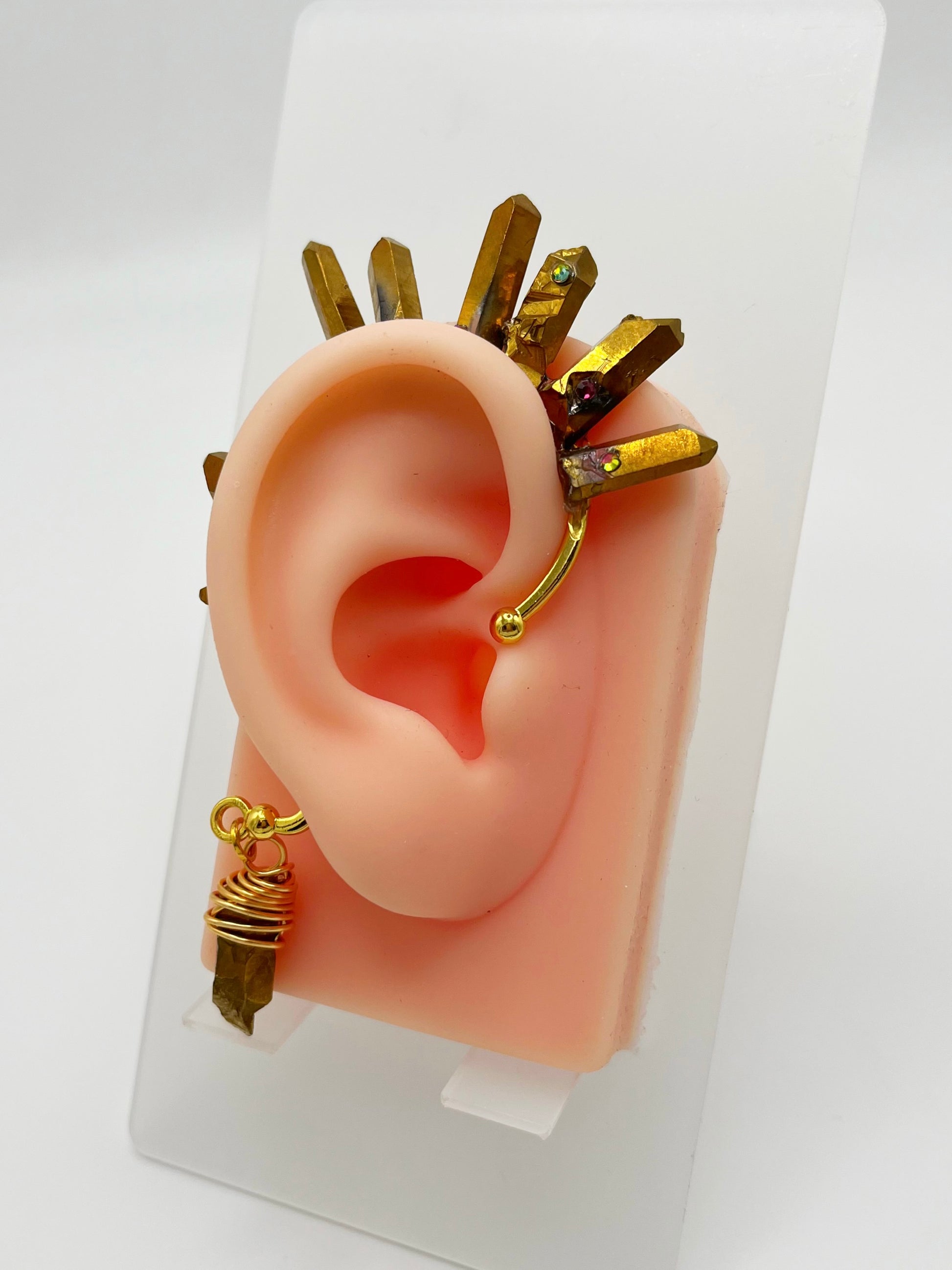 Gold pyrite quartz crystal ear cuff with rhinestones, modeled on an ear. A wire wrapped stone hangs from the bottom of the cuff behind the ear.