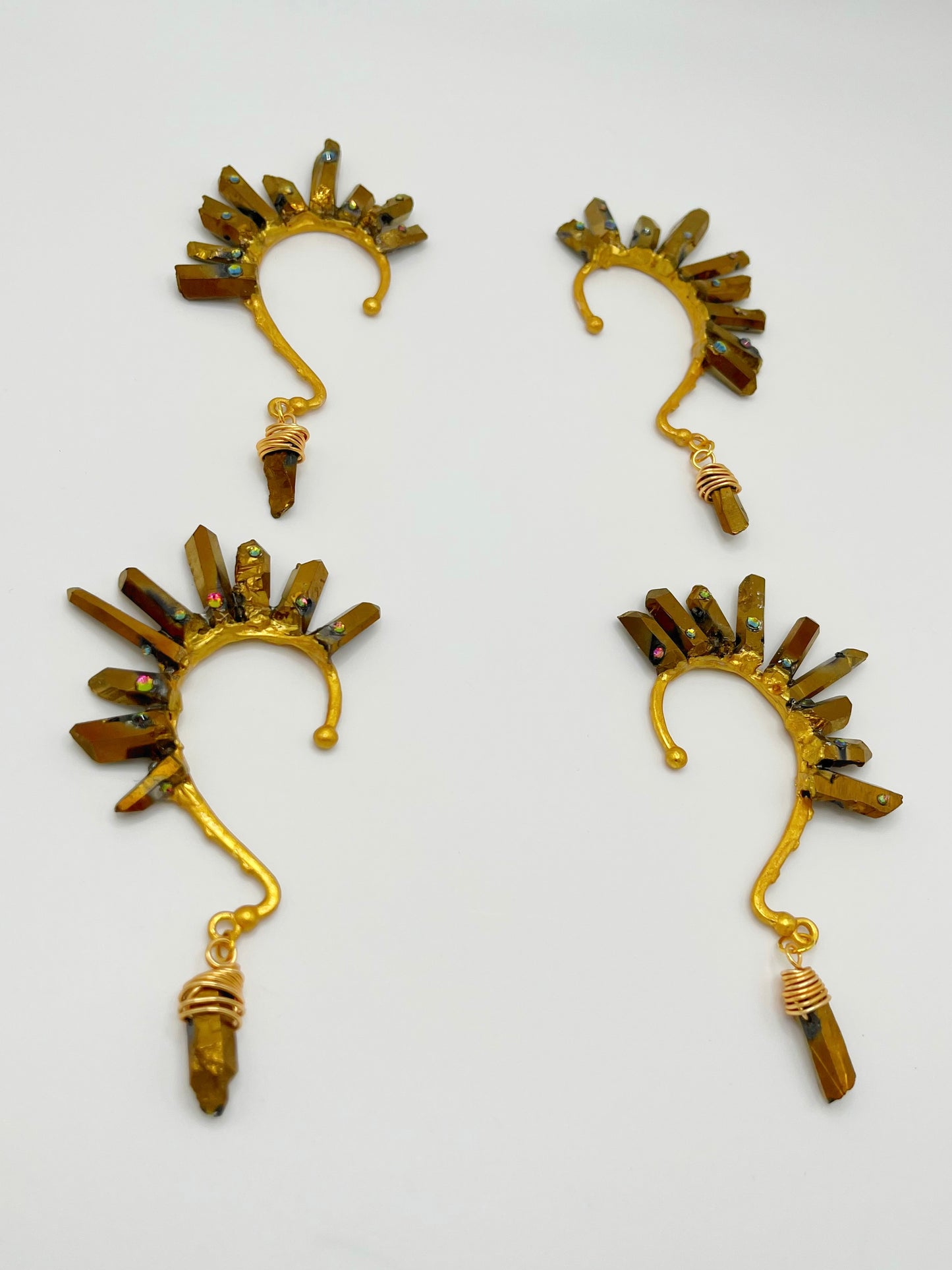Four gold pyrite quartz crystal ear cuffs with rhinestones. A wire wrapped stone hangs from the bottom of each cuff.