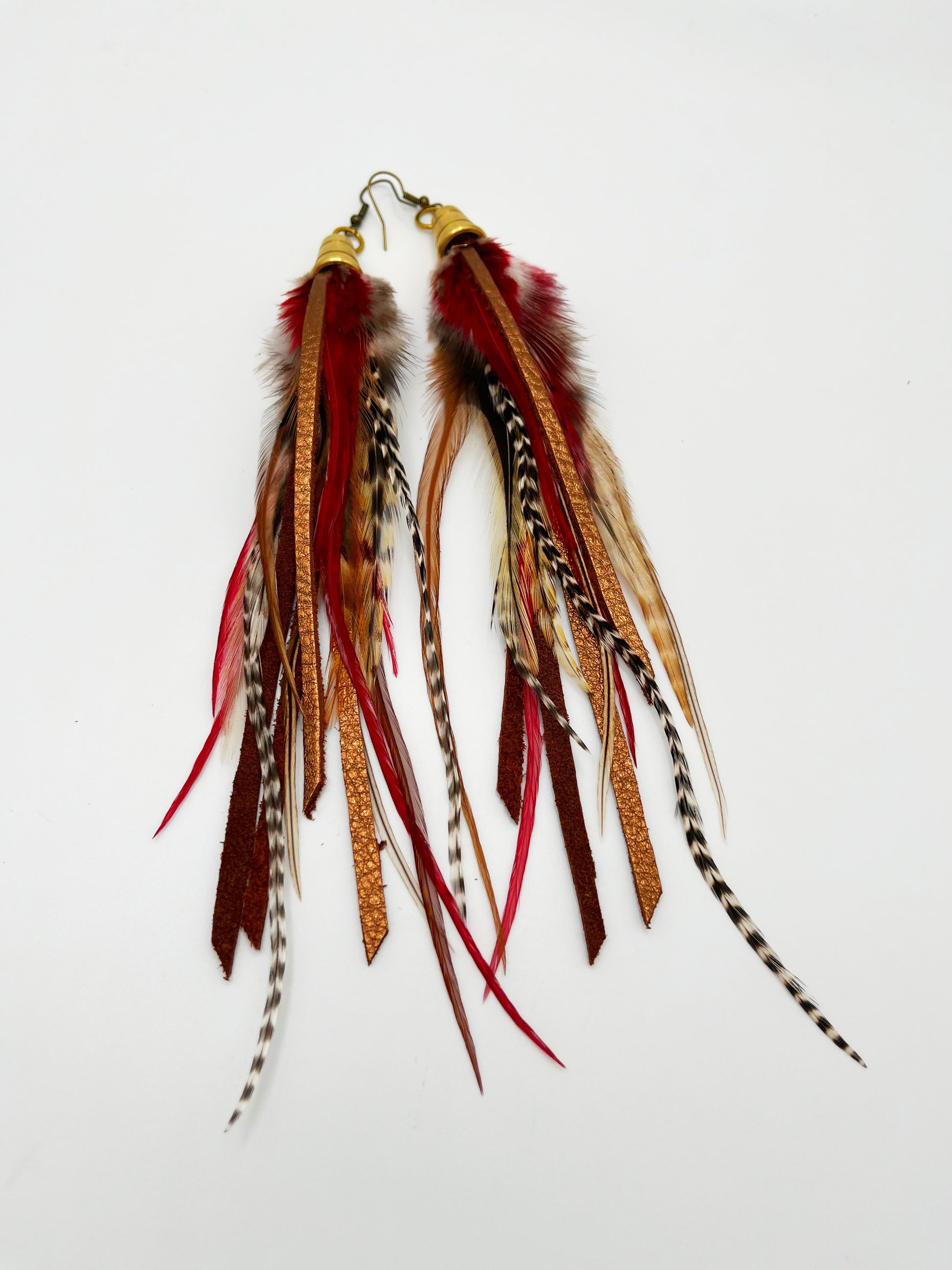 Long feather earrings in brown and deep red, with metallic bronze leather strips, hanging from a gold colored cap pendant.