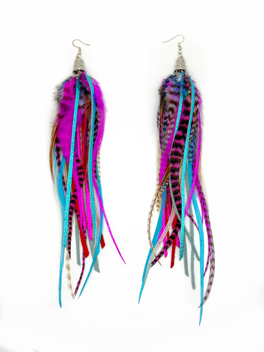 Long feather and leather earrings in neon pink and blue tones. All feathers and leather hang from underneath a silver cap pendant. 