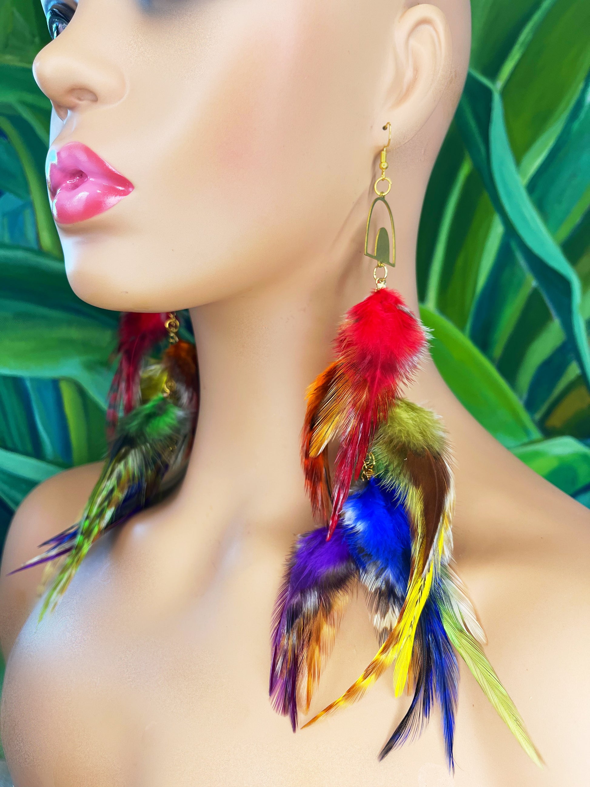 Long bohemian feather earrings in rainbow colors worn on a mannequin. 