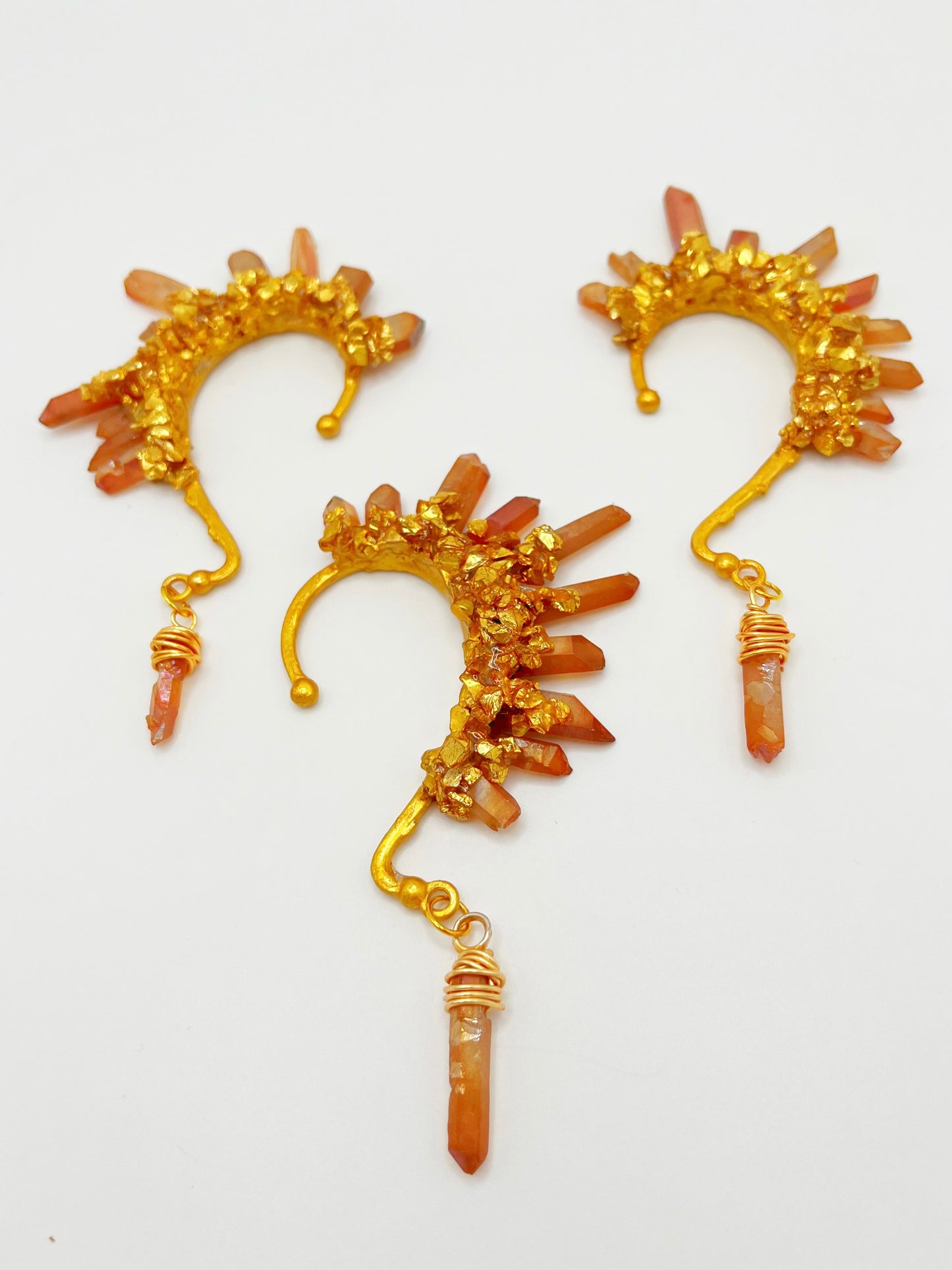 Three orange citrine crystal ear cuffs with crushed gold accents. A wire wrapped stone hangs from the bottom of each cuff.