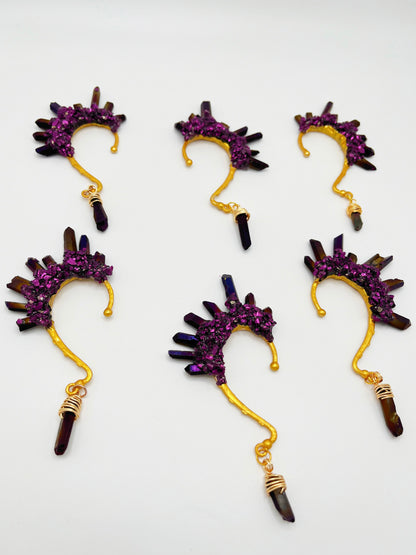 Six purple titanium coated quartz ear cuffs with a wire wrapped stone hanging from the bottom of each cuff. Each cuff is gold toned.