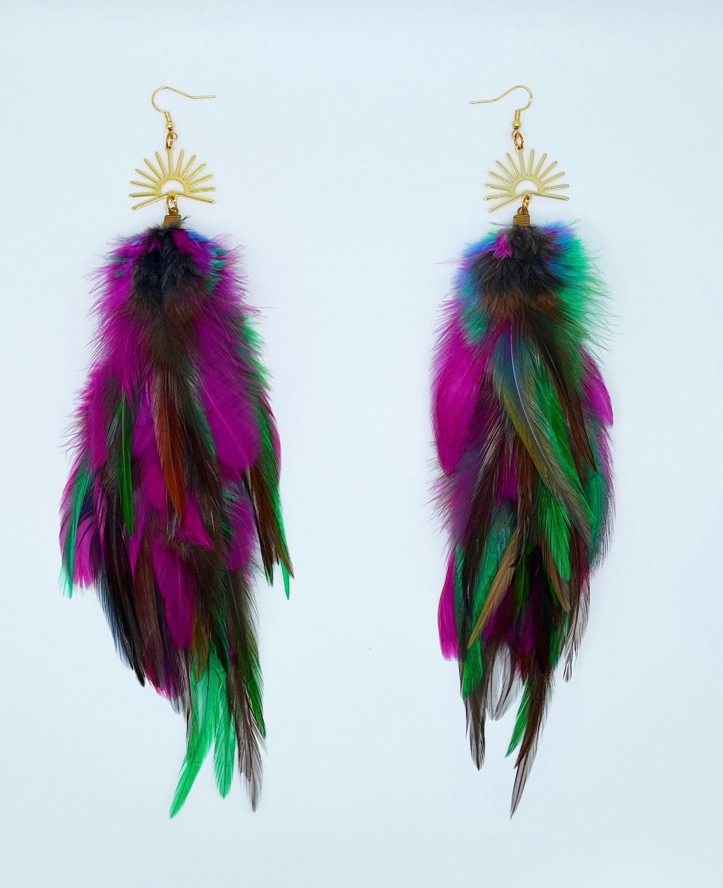 Colorful long feather earrings with gold sunburst pendants, featuring hues of purple, green, and pink against a white background, ideal for boho chic fashion.