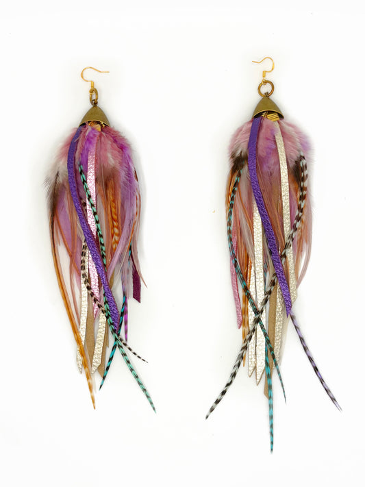 A pair of bohemian-style dangle earrings featuring multicolored feathers and metallic ribbon strands, suspended from gold-toned fishhook wires on a plain white background.