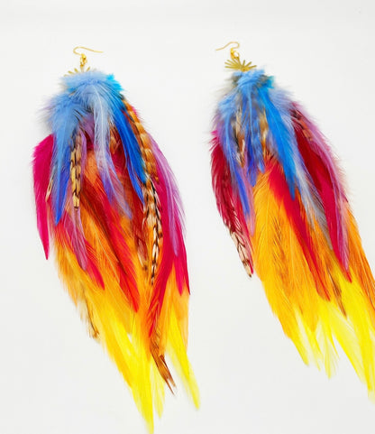 Vibrant bohemian feather earrings with blue, pink, orange and yellow feathers that hang from a gold sun pendant.