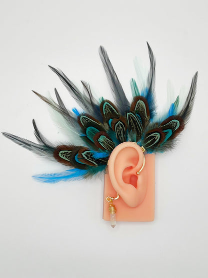 Turquoise blue, mint green and gray pheasant and rooster feather ear cuff modeled on an ear. A wire wrapped quartz stone hangs from the bottom of the cuff behind the ear. 