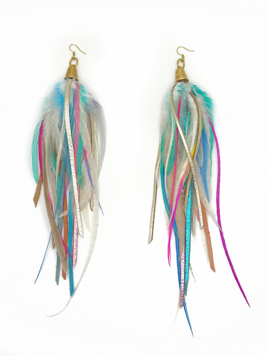 Long feather and leather earrings in white and vibrant pastel rainbow colors. Feathers and leather hang from beneath a gold cap pendant. 