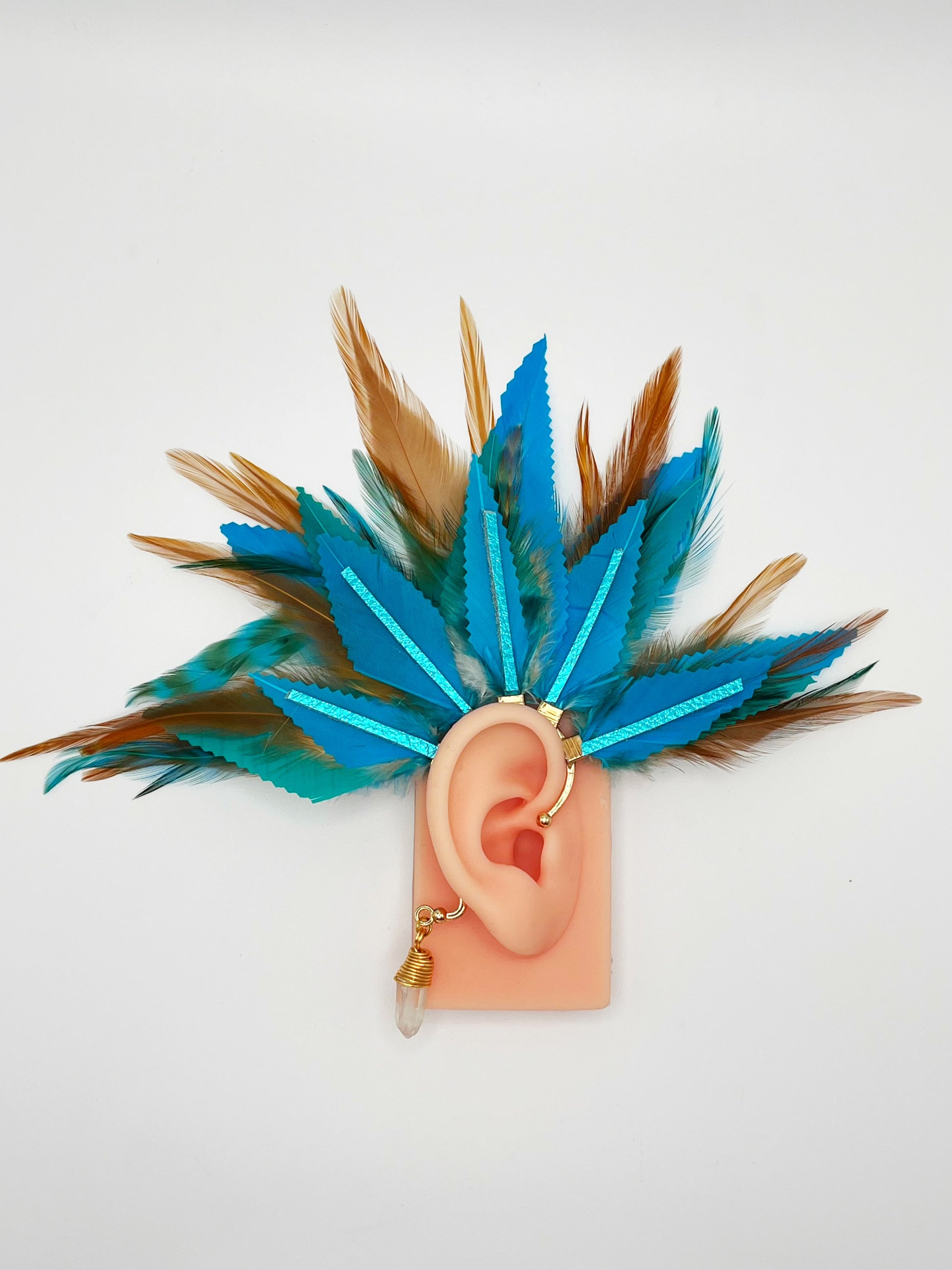 Turquoise blue and light brown feather ear cuff with blue leather accents and wire wrapped quartz dangle, modeled on an ear.