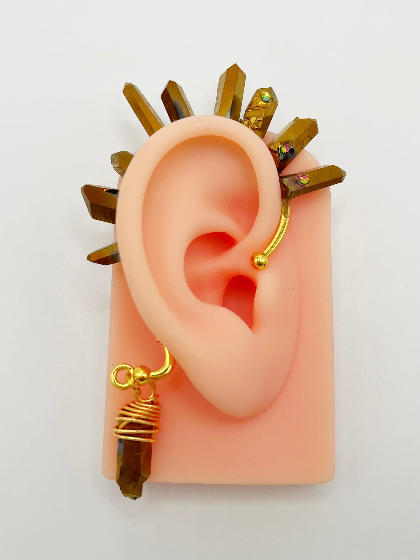 Gold pyrite quartz crystal ear cuff with rhinestones, modeled on an ear. A wire wrapped stone hangs from the bottom of the cuff behind the ear.